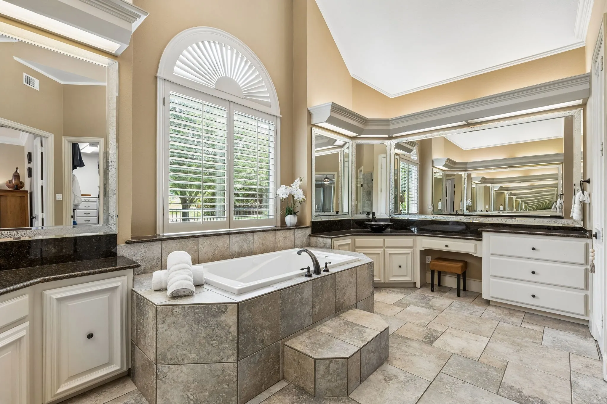 Primary spa bath with extensive counter space, separate vanities, vaulted ceilings, and frameless glass walk-in shower.
