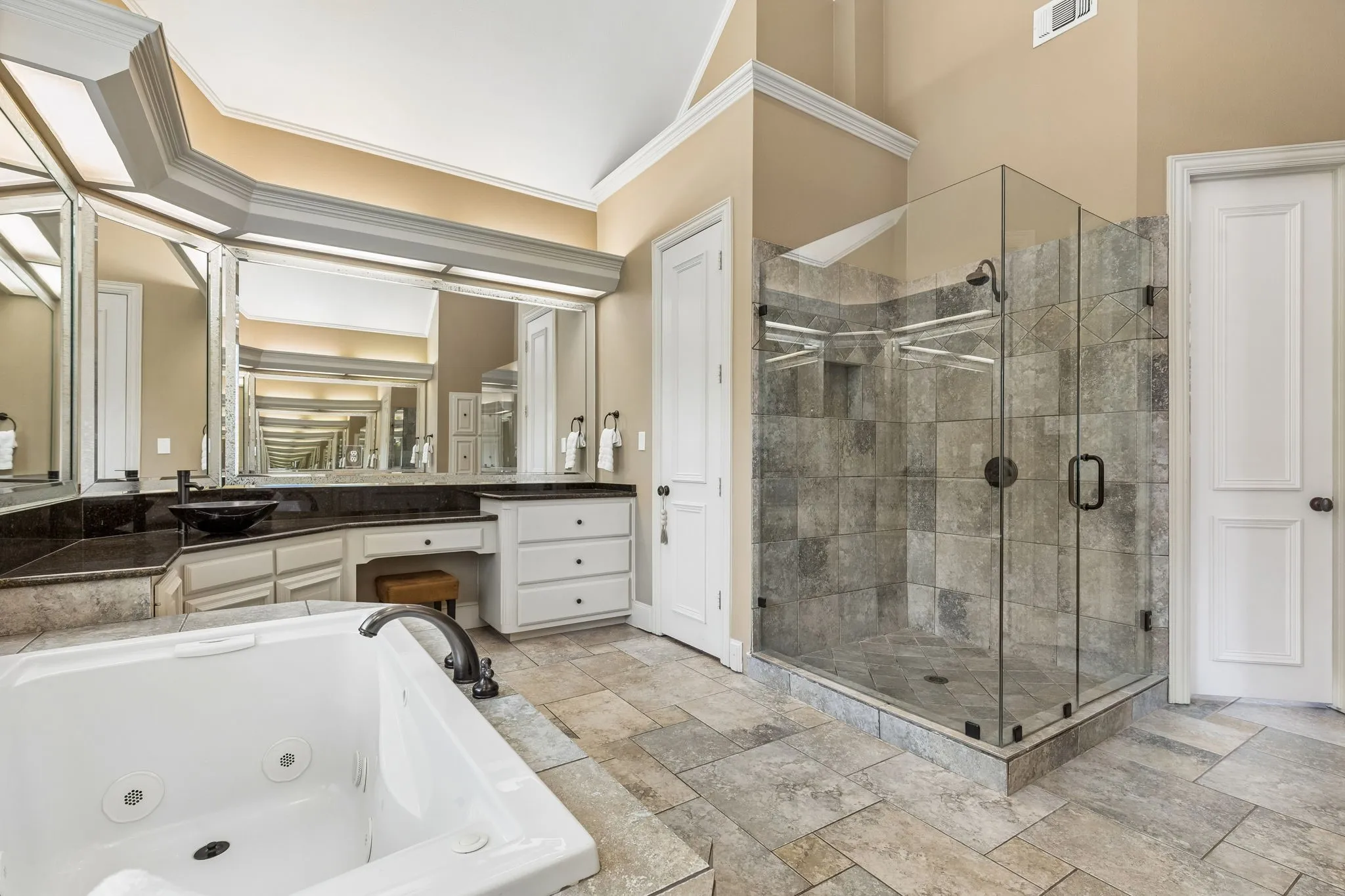 Primary spa bath with extensive counter space, separate vanities, vaulted ceilings, and frameless glass walk-in shower.