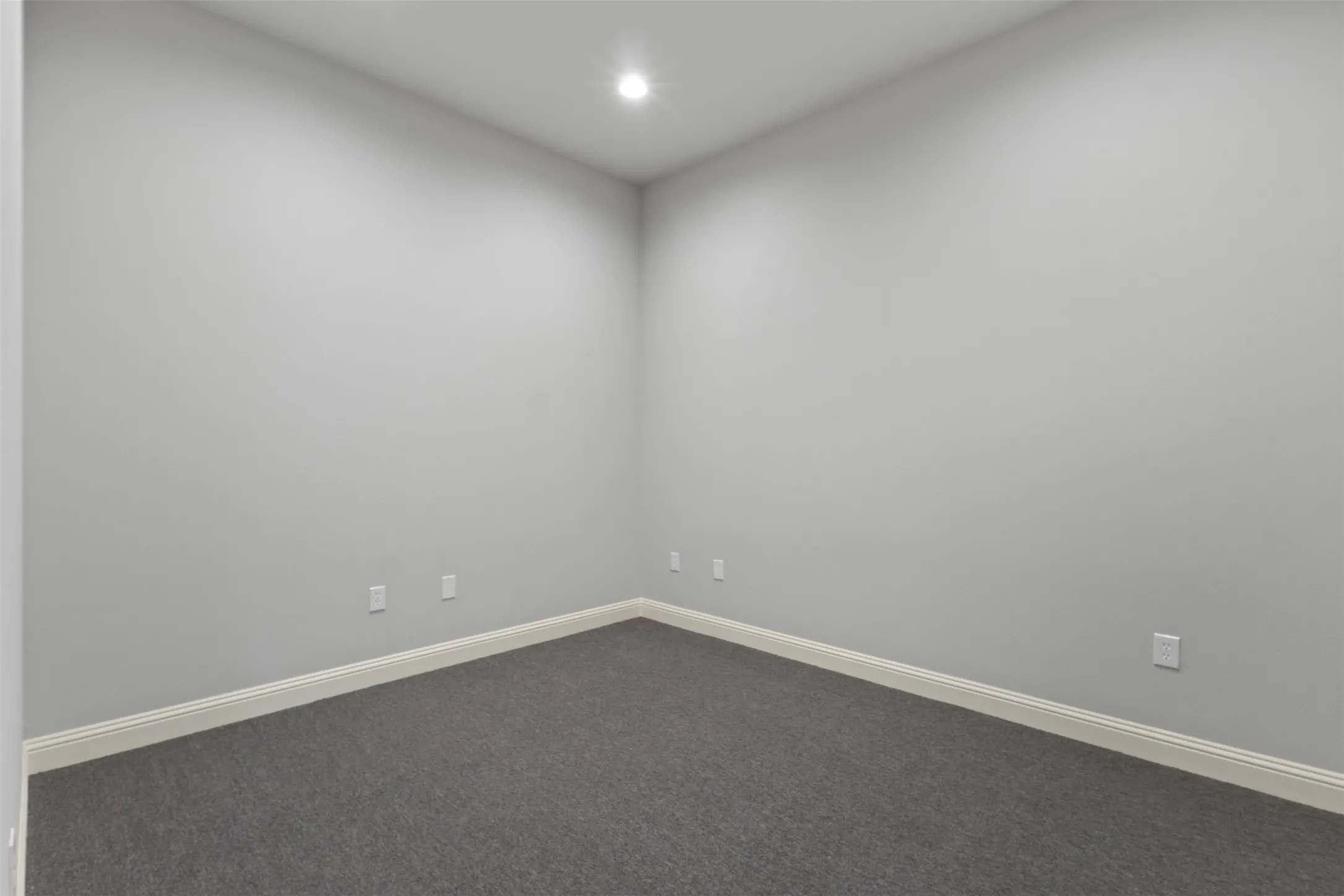 Room featuring light gray painted walls, recessed ceiling lighting, and dark gray carpeting