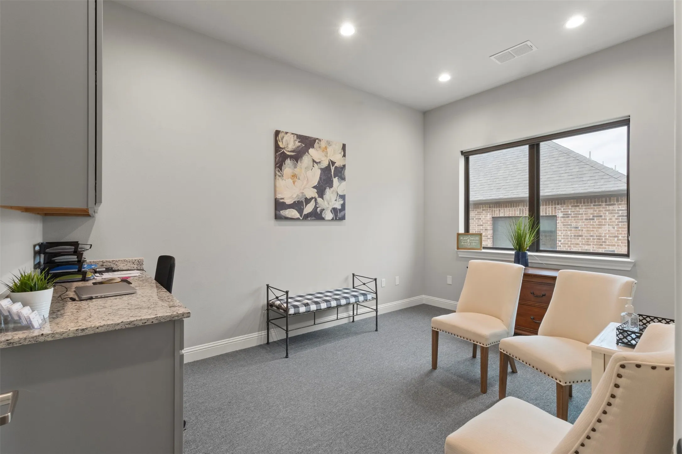 Versatile room featuring a built-in granite-finish desk with cabinetry, recessed lighting, and expansive window with exterior brick elevation