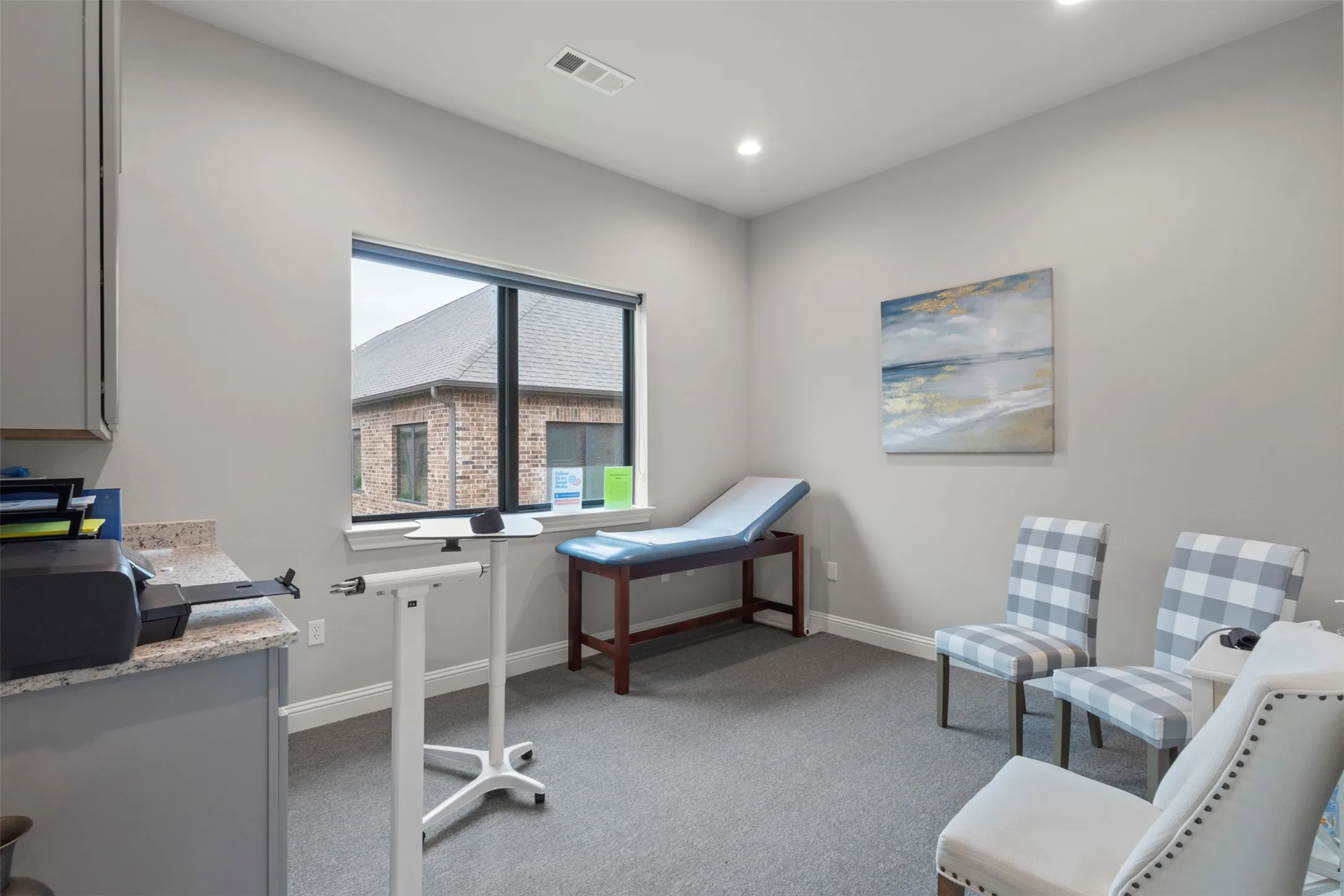 Room featuring a large window, light gray walls, gray carpet flooring, and recessed ceiling lighting