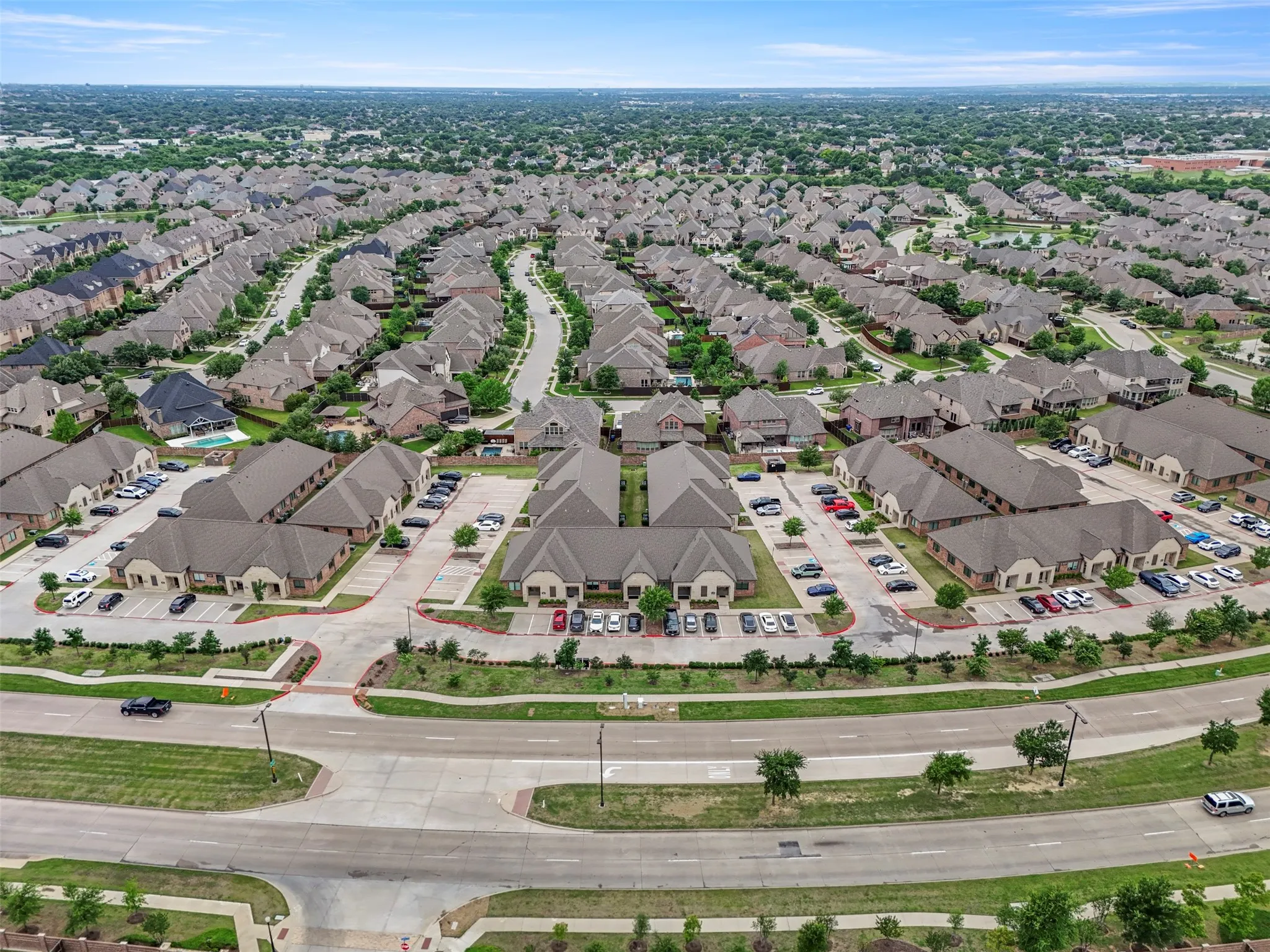 Expansive residential and commercial development featuring multiple buildings with gabled roofs, asphalt parking areas, and mature landscaping