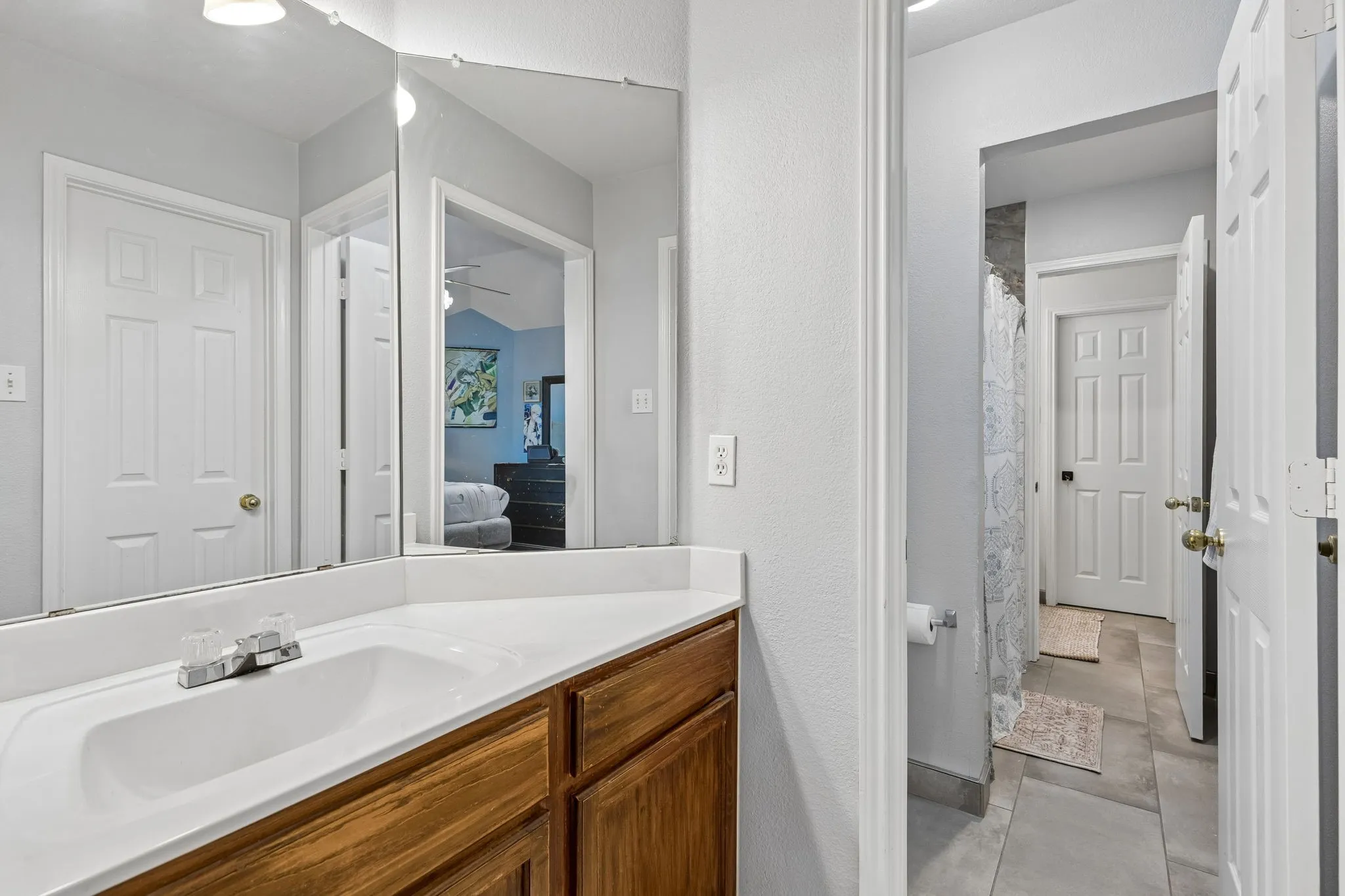 Bathroom vanity featuring a white countertop with integrated sink, wood-finish cabinetry, and chrome fixtures