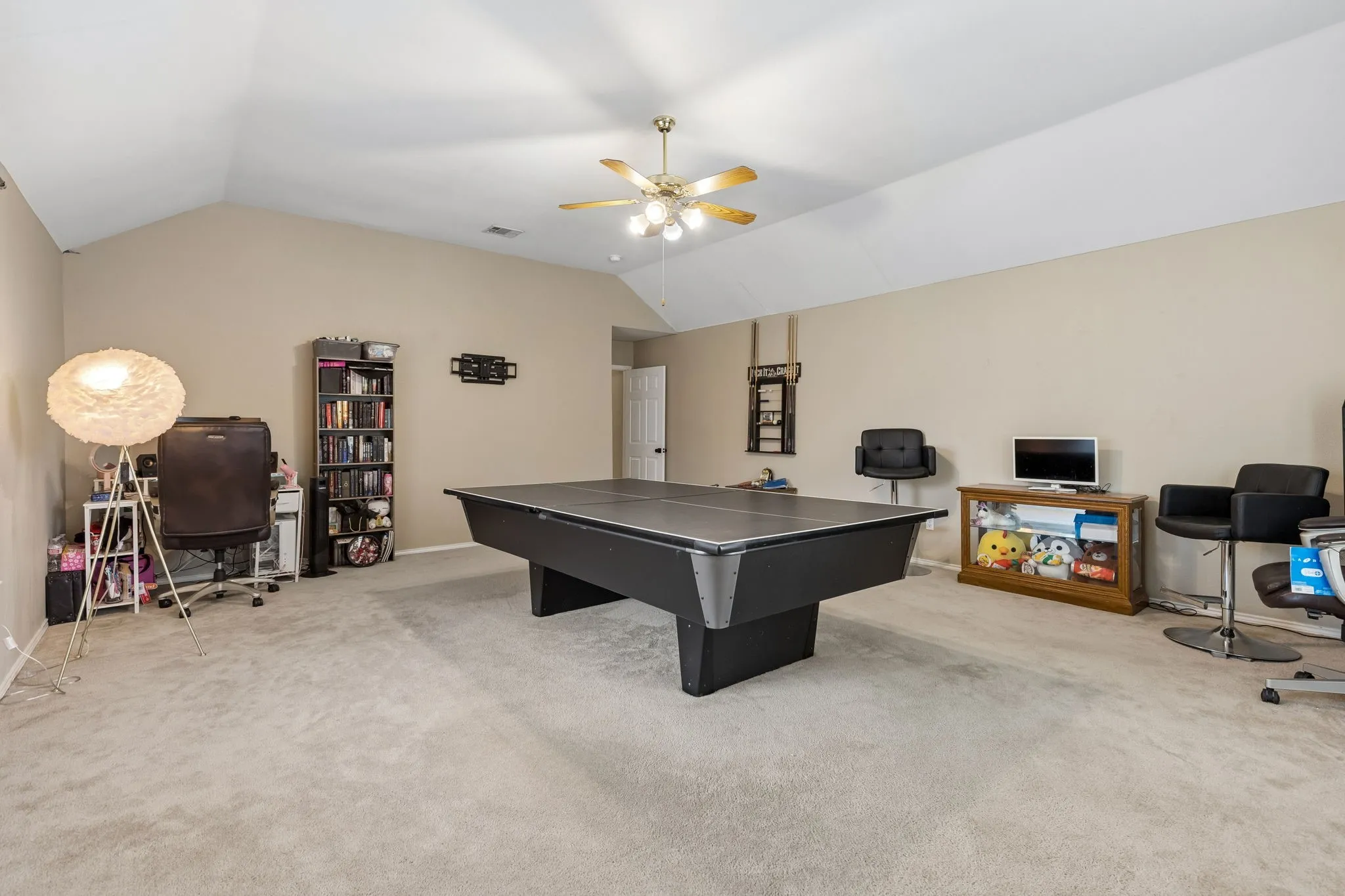 Spacious bonus room featuring vaulted ceilings, a ceiling fan with integrated lighting, and neutral carpeting