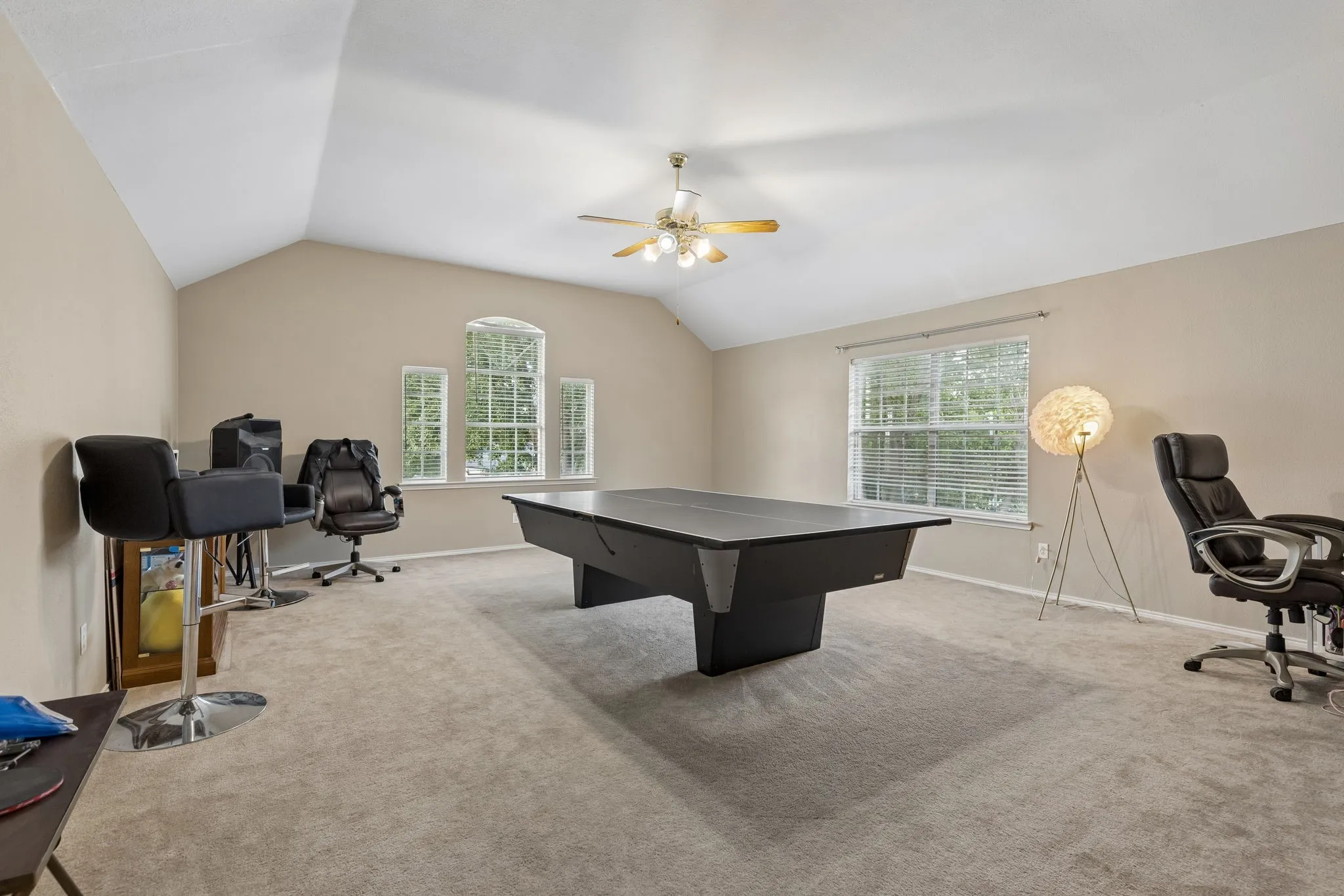 Spacious bonus room featuring vaulted ceilings, light-colored carpeting, multiple windows for natural light, and a ceiling fan