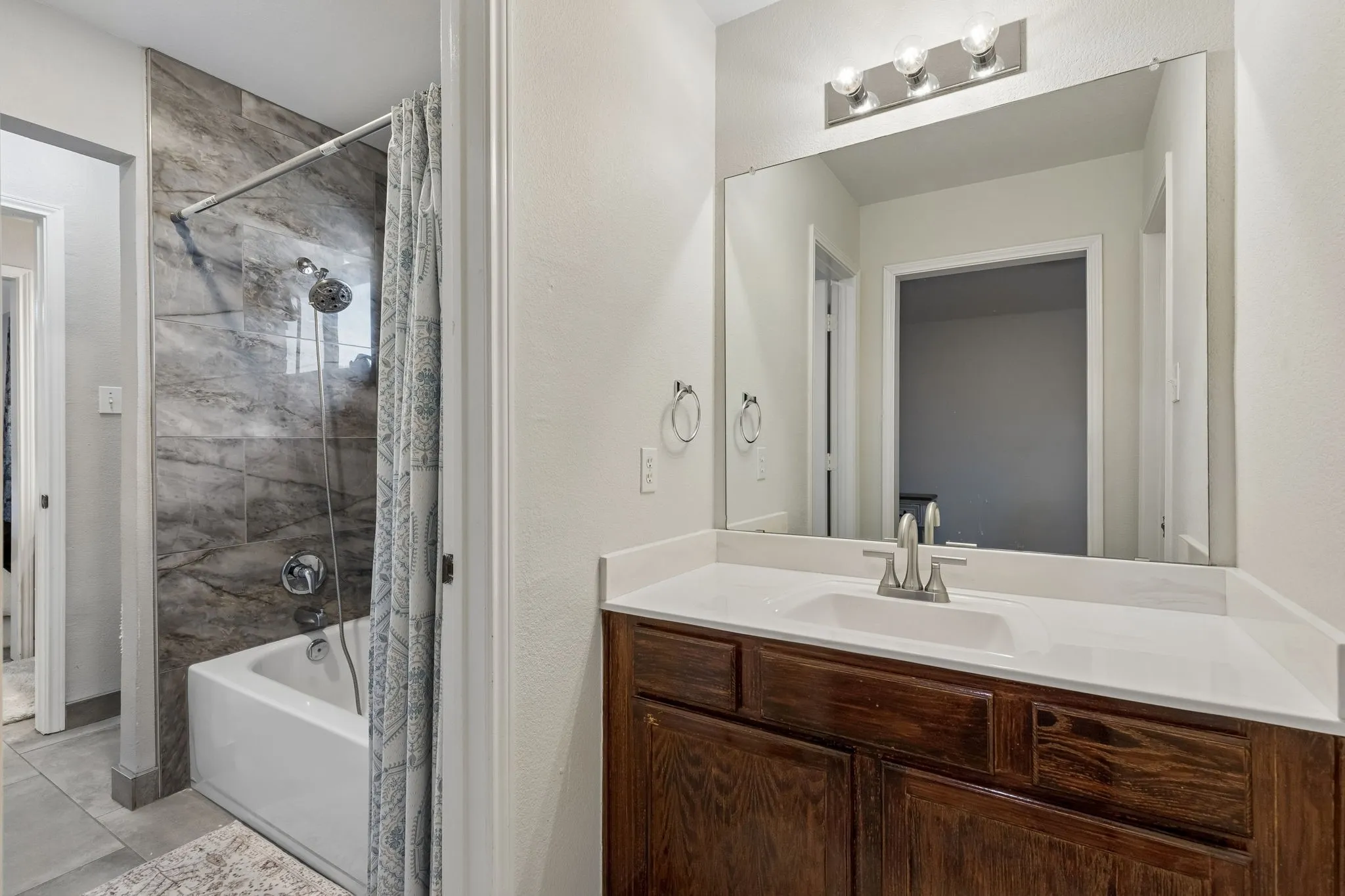 Bathroom featuring a vanity with dark wood-finish cabinetry, a white countertop, and an integrated sink with a brushed nickel faucet
