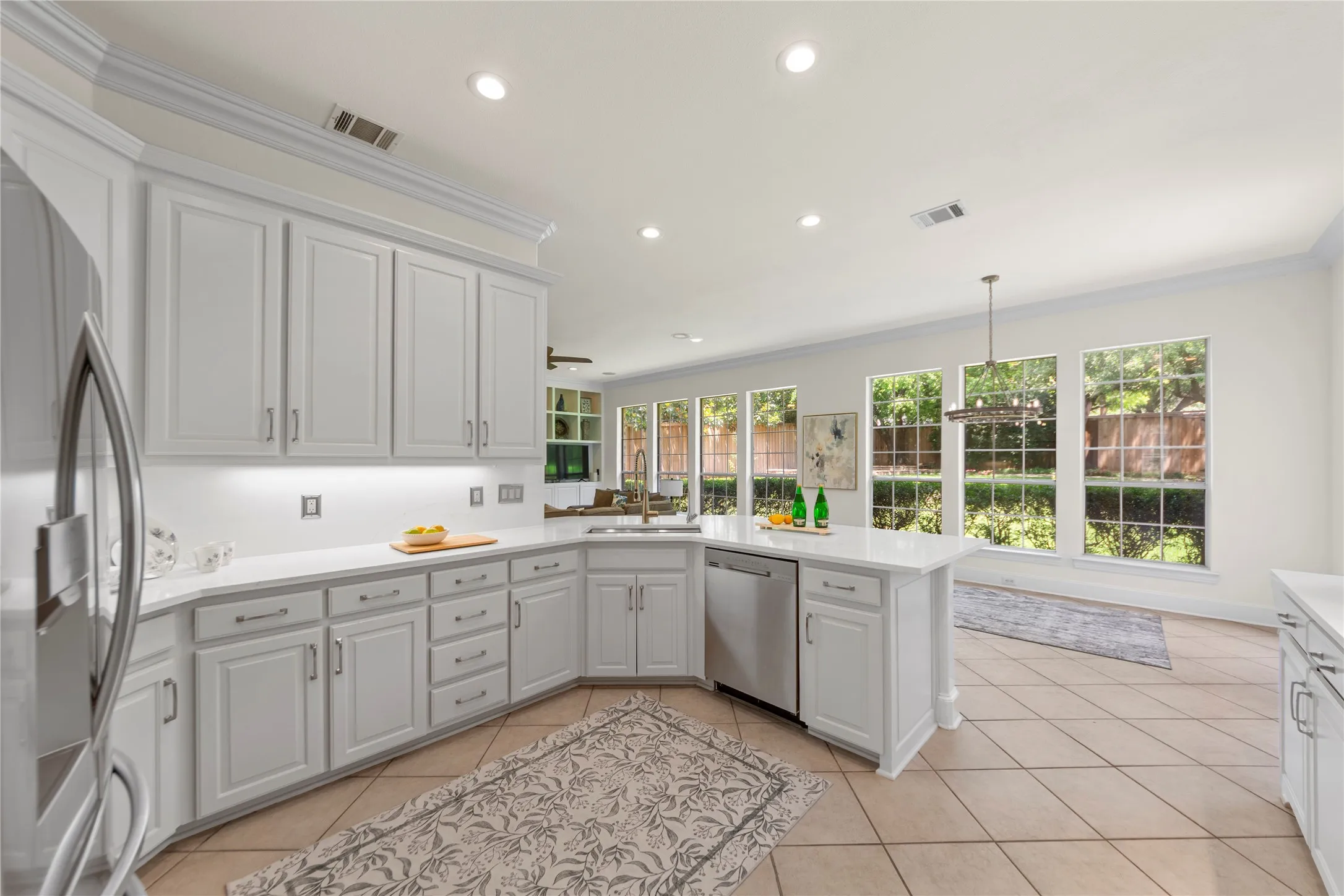 The beautifully updated kitchen is bright, modern, and designed for both everyday living and entertaining. Featuring new quartz countertops, fresh designer paint, updated cabinetry, a stunning new vent hood, and new stainless steel appliances, the space blends timeless elegance with modern functionality. Oversized windows fill the kitchen and breakfast area with natural light while offering peaceful views of the lush backyard and pool.Open to the spacious family room, this inviting layout creates the perfect gathering space for family and guests alike. The large family room showcases a striking floor-to-ceiling stone fireplace, custom built-ins, recessed lighting, and walls of windows that bring the outdoors in. Light, bright, and airy throughout, this open-concept living area feels warm, welcoming, and ideal for entertaining.