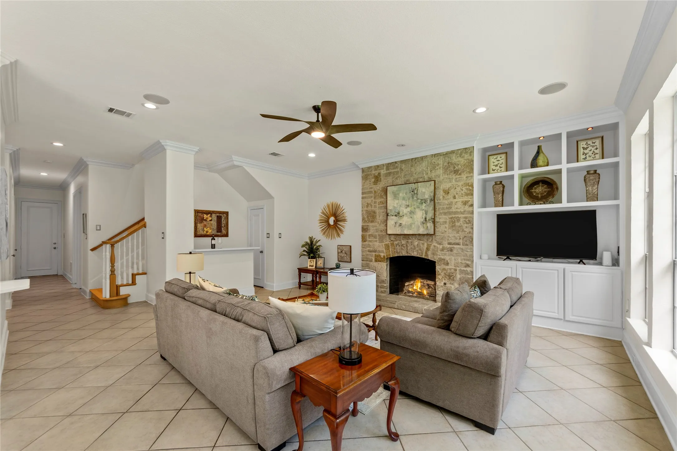 The beautifully updated kitchen is bright, modern, and designed for both everyday living and entertaining. Featuring new quartz countertops, fresh designer paint, updated cabinetry, a stunning new vent hood, and new stainless steel appliances, the space blends timeless elegance with modern functionality. Oversized windows fill the kitchen and breakfast area with natural light while offering peaceful views of the lush backyard and pool.Open to the spacious family room, this inviting layout creates the perfect gathering space for family and guests alike. The large family room showcases a striking floor-to-ceiling stone fireplace, custom built-ins, recessed lighting, and walls of windows that bring the outdoors in. Light, bright, and airy throughout, this open-concept living area feels warm, welcoming, and ideal for entertaining.