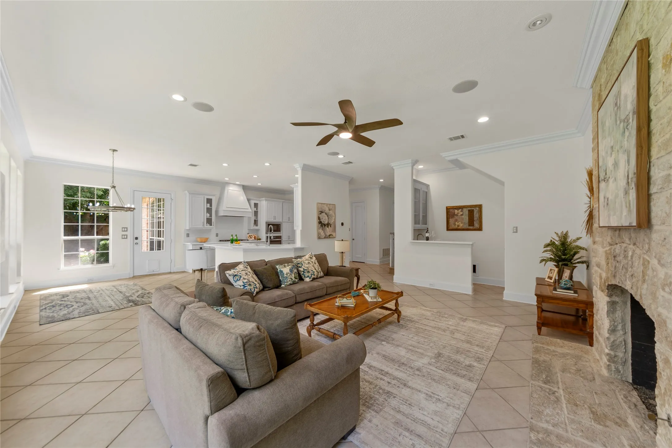 The beautifully updated kitchen is bright, modern, and designed for both everyday living and entertaining. Featuring new quartz countertops, fresh designer paint, updated cabinetry, a stunning new vent hood, and new stainless steel appliances, the space blends timeless elegance with modern functionality. Oversized windows fill the kitchen and breakfast area with natural light while offering peaceful views of the lush backyard and pool.Open to the spacious family room, this inviting layout creates the perfect gathering space for family and guests alike. The large family room showcases a striking floor-to-ceiling stone fireplace, custom built-ins, recessed lighting, and walls of windows that bring the outdoors in. Light, bright, and airy throughout, this open-concept living area feels warm, welcoming, and ideal for entertaining.