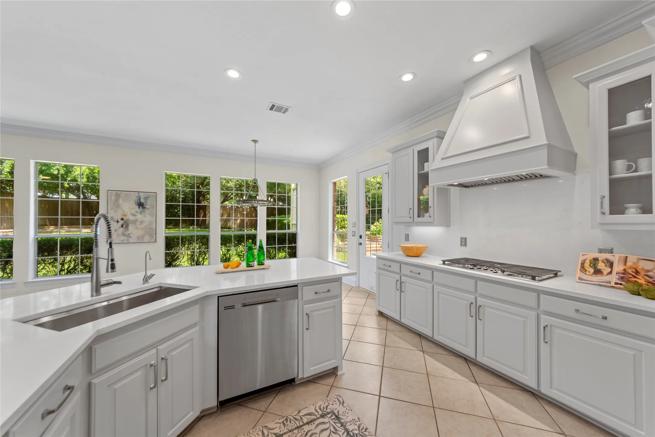 The beautifully updated kitchen is bright, modern, and designed for both everyday living and entertaining. Featuring new quartz countertops, fresh designer paint, updated cabinetry, a stunning new vent hood, and new stainless steel appliances, the space blends timeless elegance with modern functionality. Oversized windows fill the kitchen and breakfast area with natural light while offering peaceful views of the lush backyard and pool.Open to the spacious family room, this inviting layout creates the perfect gathering space for family and guests alike. The large family room showcases a striking floor-to-ceiling stone fireplace, custom built-ins, recessed lighting, and walls of windows that bring the outdoors in. Light, bright, and airy throughout, this open-concept living area feels warm, welcoming, and ideal for entertaining.