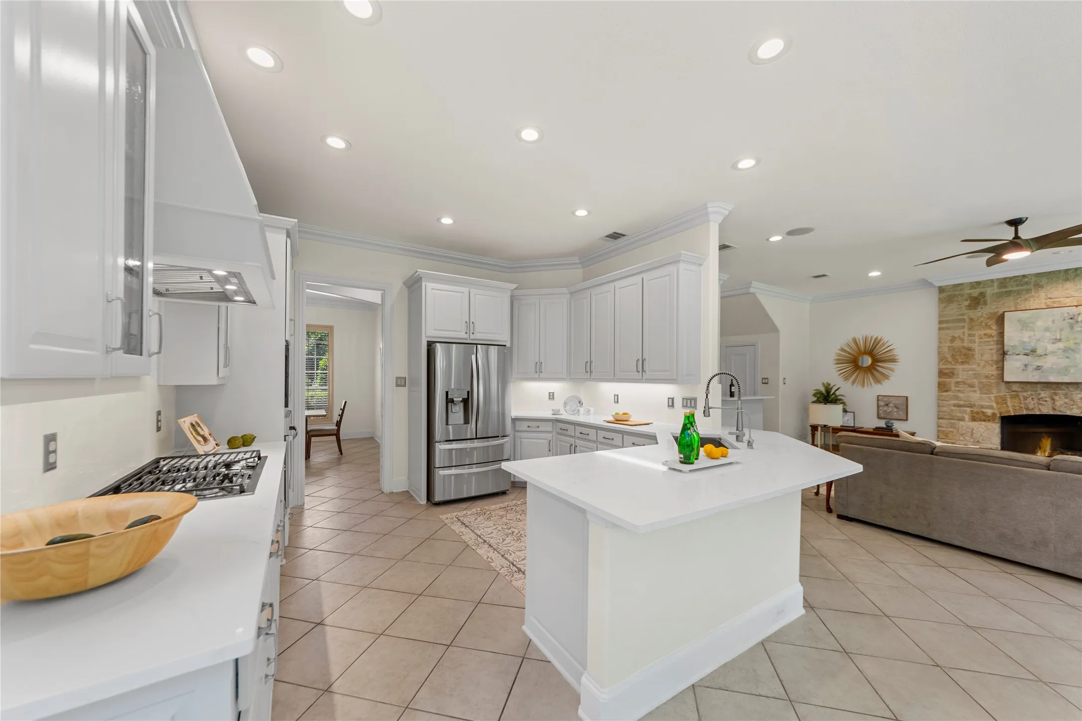 The beautifully updated kitchen is bright, modern, and designed for both everyday living and entertaining. Featuring new quartz countertops, fresh designer paint, updated cabinetry, a stunning new vent hood, and new stainless steel appliances, the space blends timeless elegance with modern functionality. Oversized windows fill the kitchen and breakfast area with natural light while offering peaceful views of the lush backyard and pool.Open to the spacious family room, this inviting layout creates the perfect gathering space for family and guests alike. The large family room showcases a striking floor-to-ceiling stone fireplace, custom built-ins, recessed lighting, and walls of windows that bring the outdoors in. Light, bright, and airy throughout, this open-concept living area feels warm, welcoming, and ideal for entertaining.