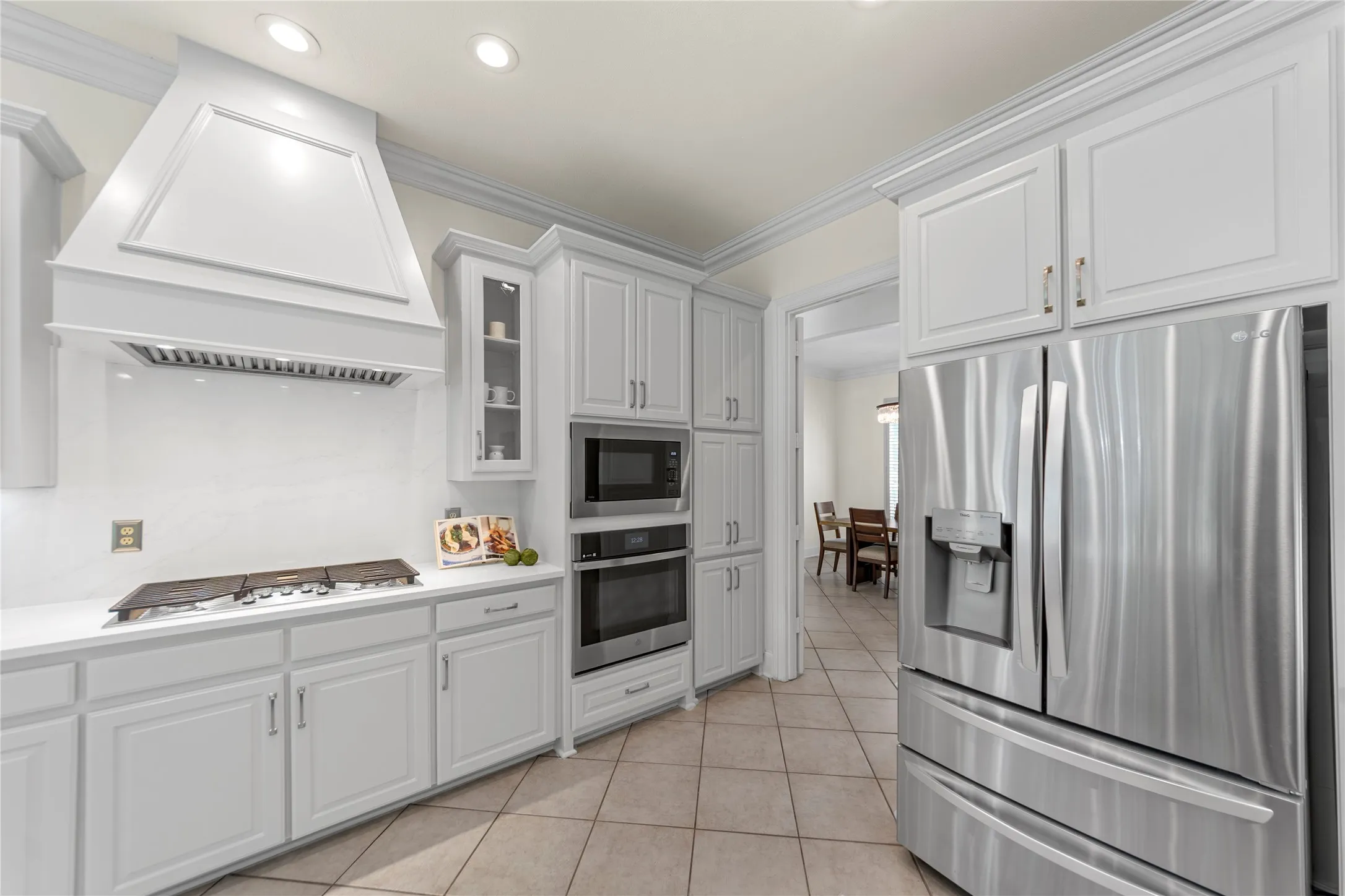 The beautifully updated kitchen is bright, modern, and designed for both everyday living and entertaining. Featuring new quartz countertops, fresh designer paint, updated cabinetry, a stunning new vent hood, and new stainless steel appliances, the space blends timeless elegance with modern functionality. Oversized windows fill the kitchen and breakfast area with natural light while offering peaceful views of the lush backyard and pool.Open to the spacious family room, this inviting layout creates the perfect gathering space for family and guests alike. The large family room showcases a striking floor-to-ceiling stone fireplace, custom built-ins, recessed lighting, and walls of windows that bring the outdoors in. Light, bright, and airy throughout, this open-concept living area feels warm, welcoming, and ideal for entertaining.