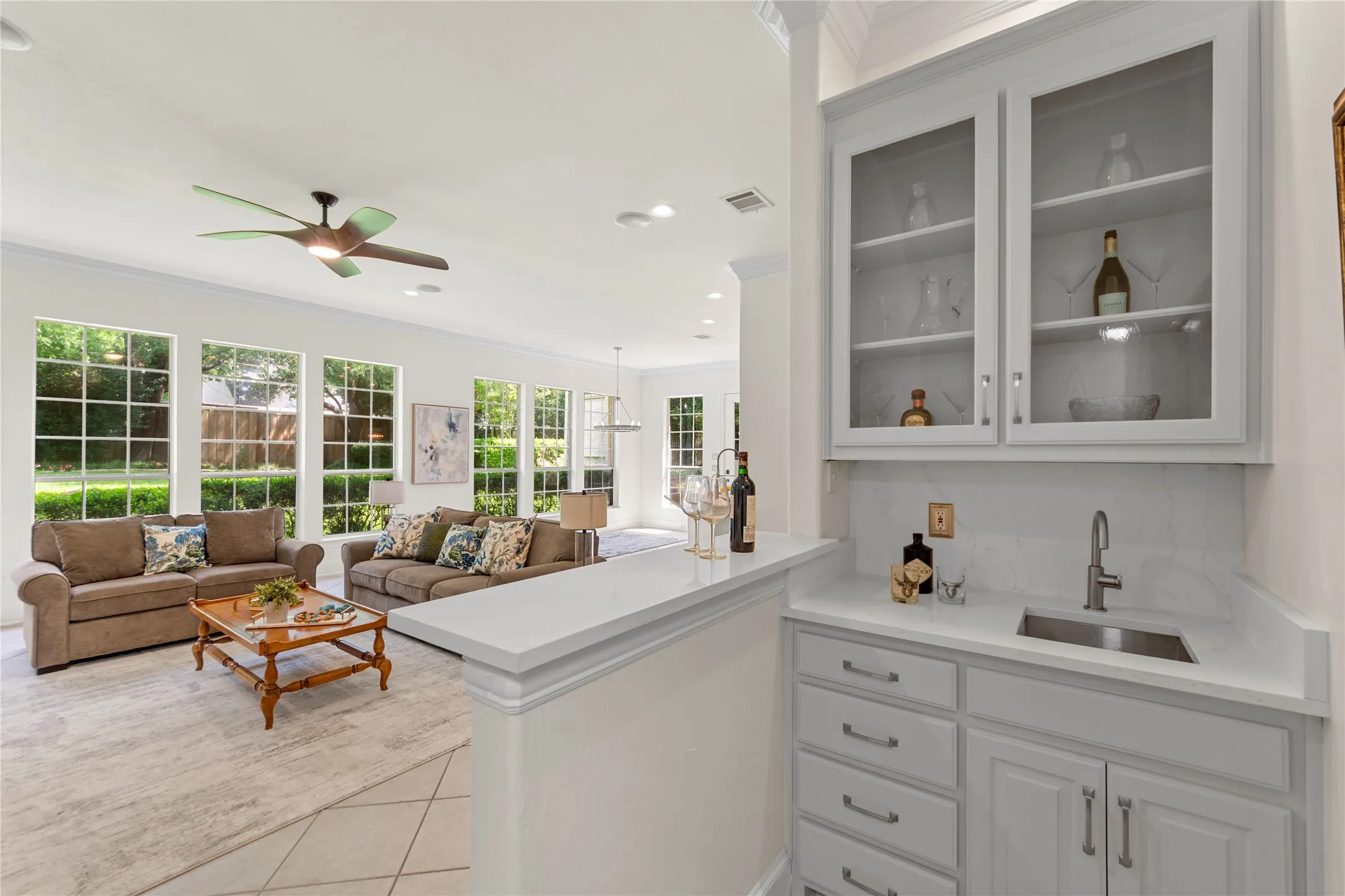 The beautifully updated kitchen is bright, modern, and designed for both everyday living and entertaining. Featuring new quartz countertops, fresh designer paint, updated cabinetry, a stunning new vent hood, and new stainless steel appliances, the space blends timeless elegance with modern functionality. Oversized windows fill the kitchen and breakfast area with natural light while offering peaceful views of the lush backyard and pool.Open to the spacious family room, this inviting layout creates the perfect gathering space for family and guests alike. The large family room showcases a striking floor-to-ceiling stone fireplace, custom built-ins, recessed lighting, and walls of windows that bring the outdoors in. Light, bright, and airy throughout, this open-concept living area feels warm, welcoming, and ideal for entertaining.