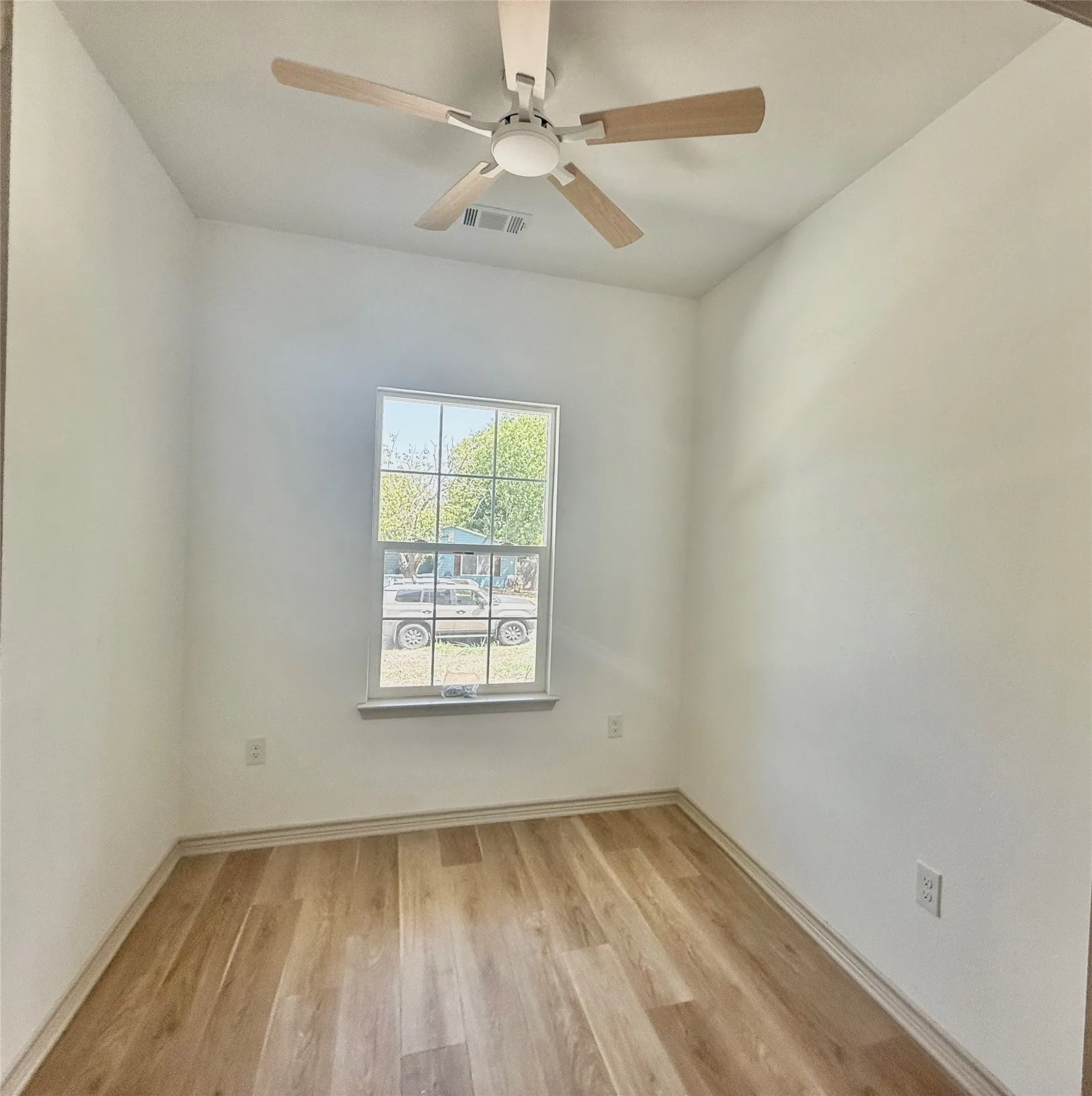 Wood-finish flooring, white walls, and a ceiling fan with light fixture