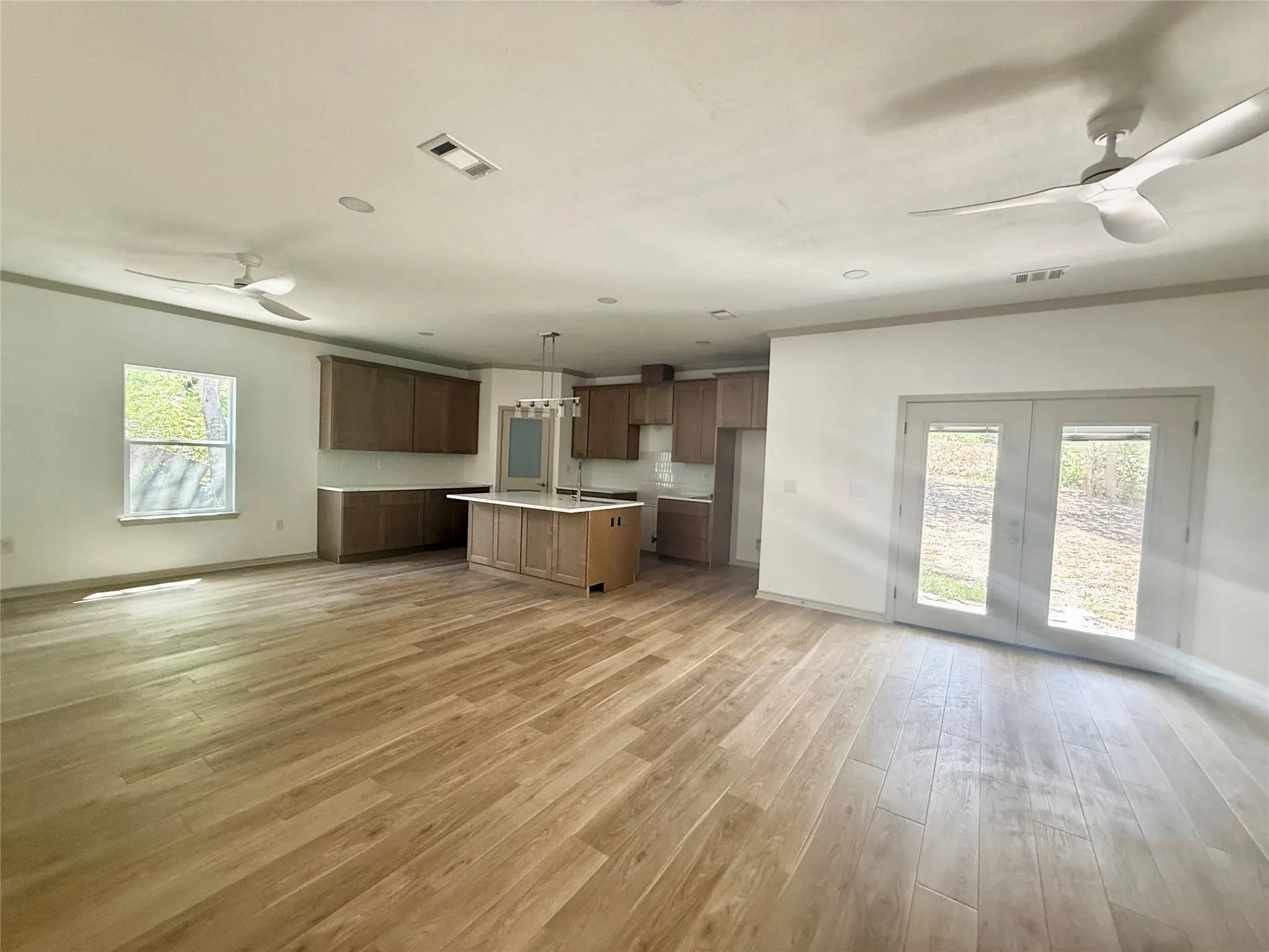 Open-concept living space with wood-finish flooring, recessed lighting, and ceiling fans