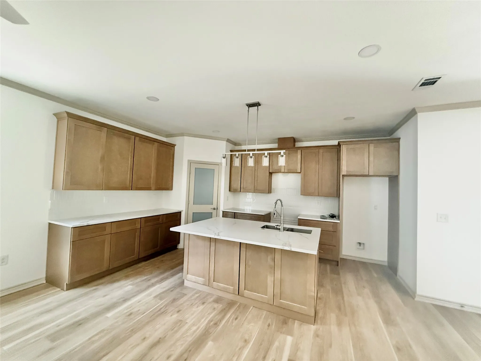 Kitchen island with white stone countertop, stainless steel sink, and contemporary pendant lighting