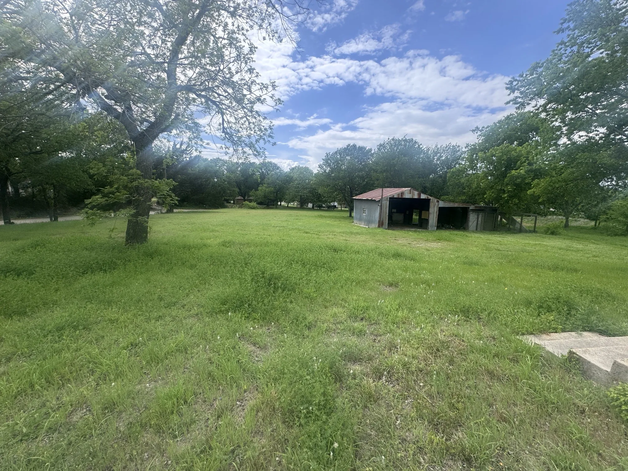 Expansive grassy outdoor space with mature trees
