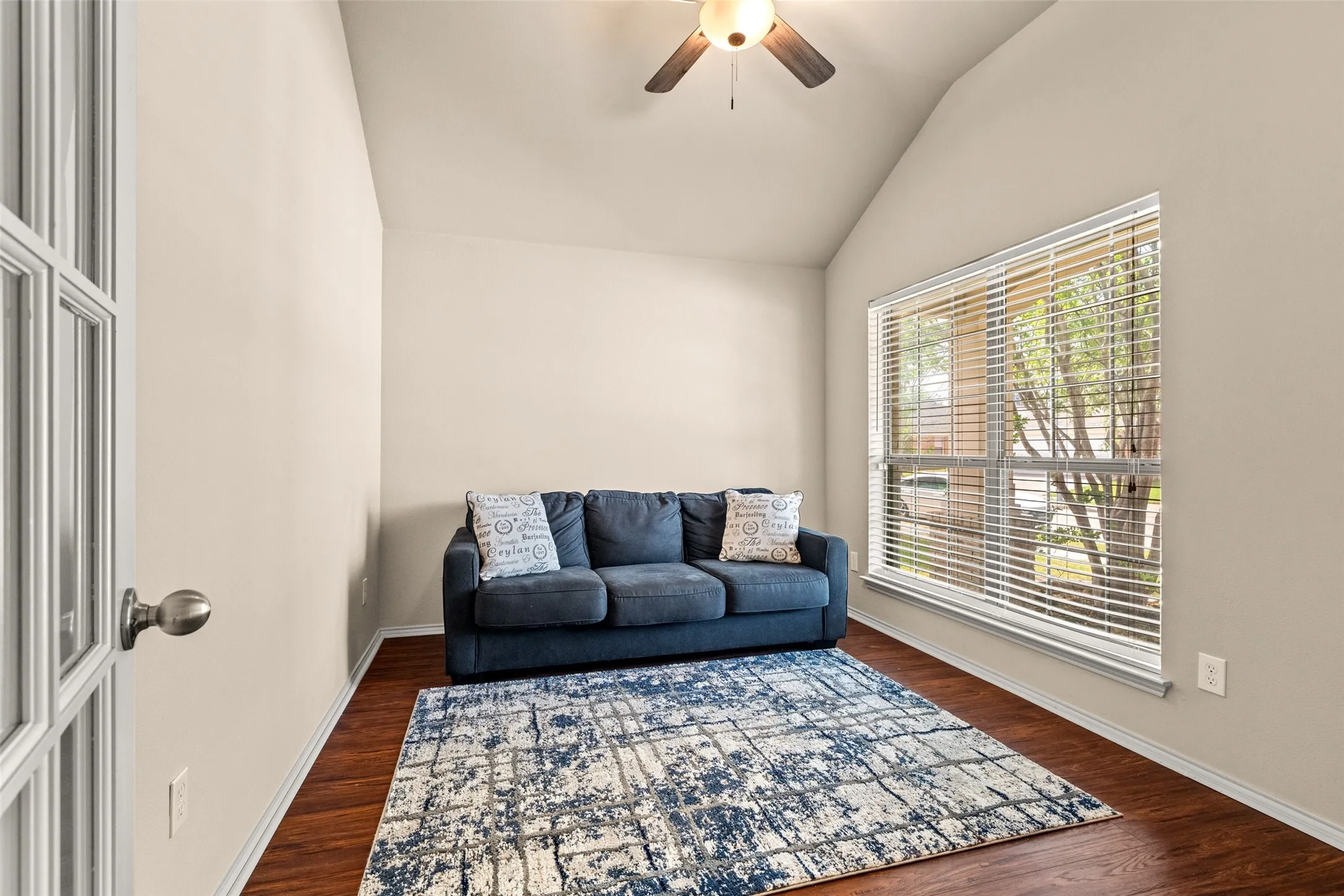 Vaulted ceiling room featuring French doors with glass panes, wood-finish flooring, a large window with blinds, and a ceiling fan with integrated lighting