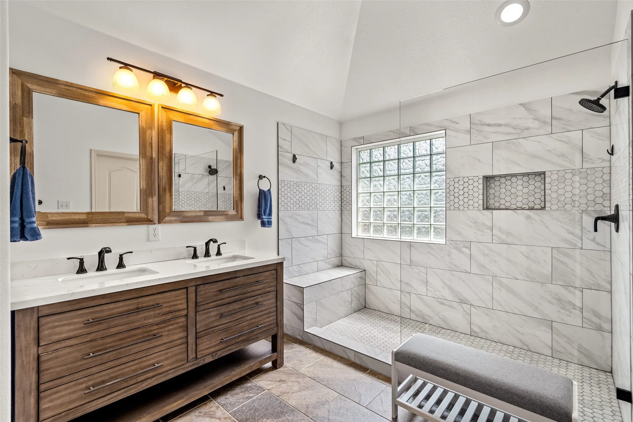 Tiled shower with a glass block window, integrated bench, and shower niche