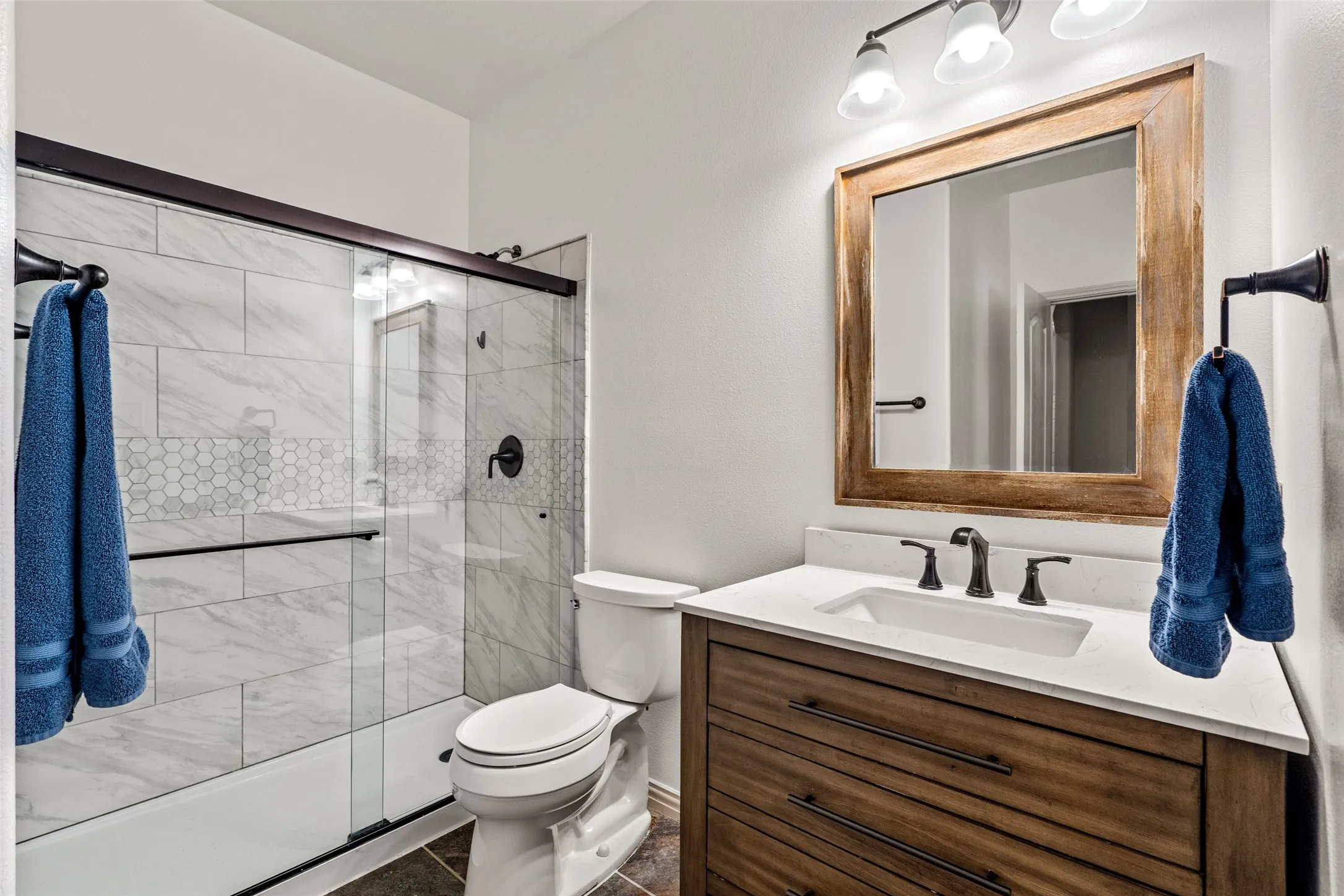 Bathroom featuring a wood-finish vanity with a white countertop and undermount sink