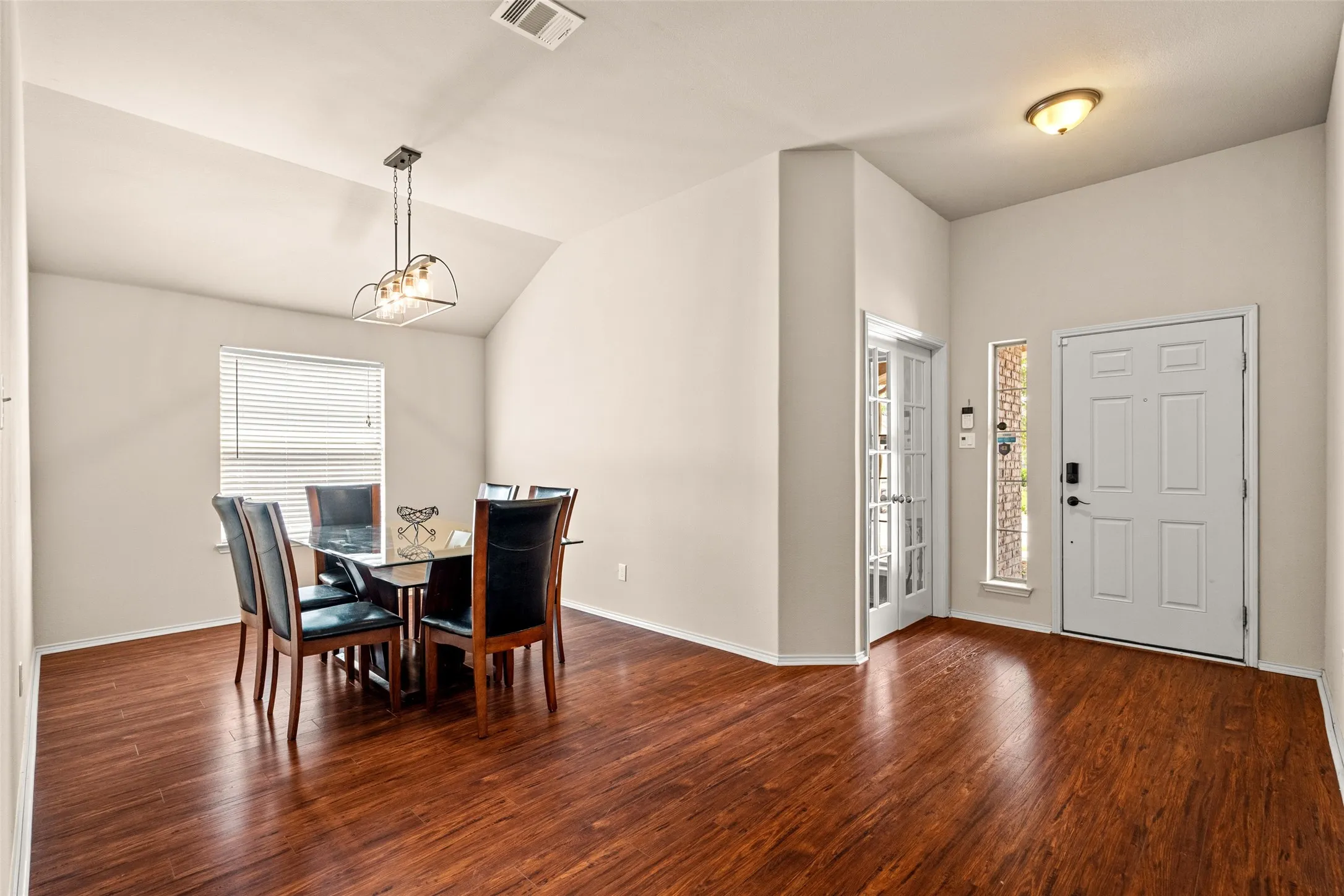Spacious interior featuring wood-finish flooring, vaulted ceiling, and neutral wall tones