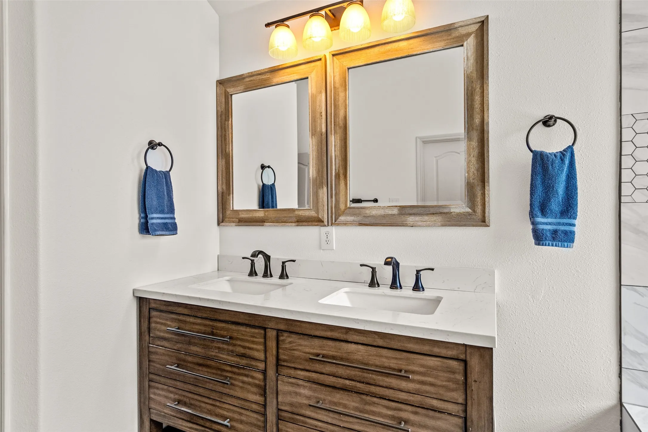 Dual vanity with wood-finish cabinetry, white countertop, and rectangular undermount sinks