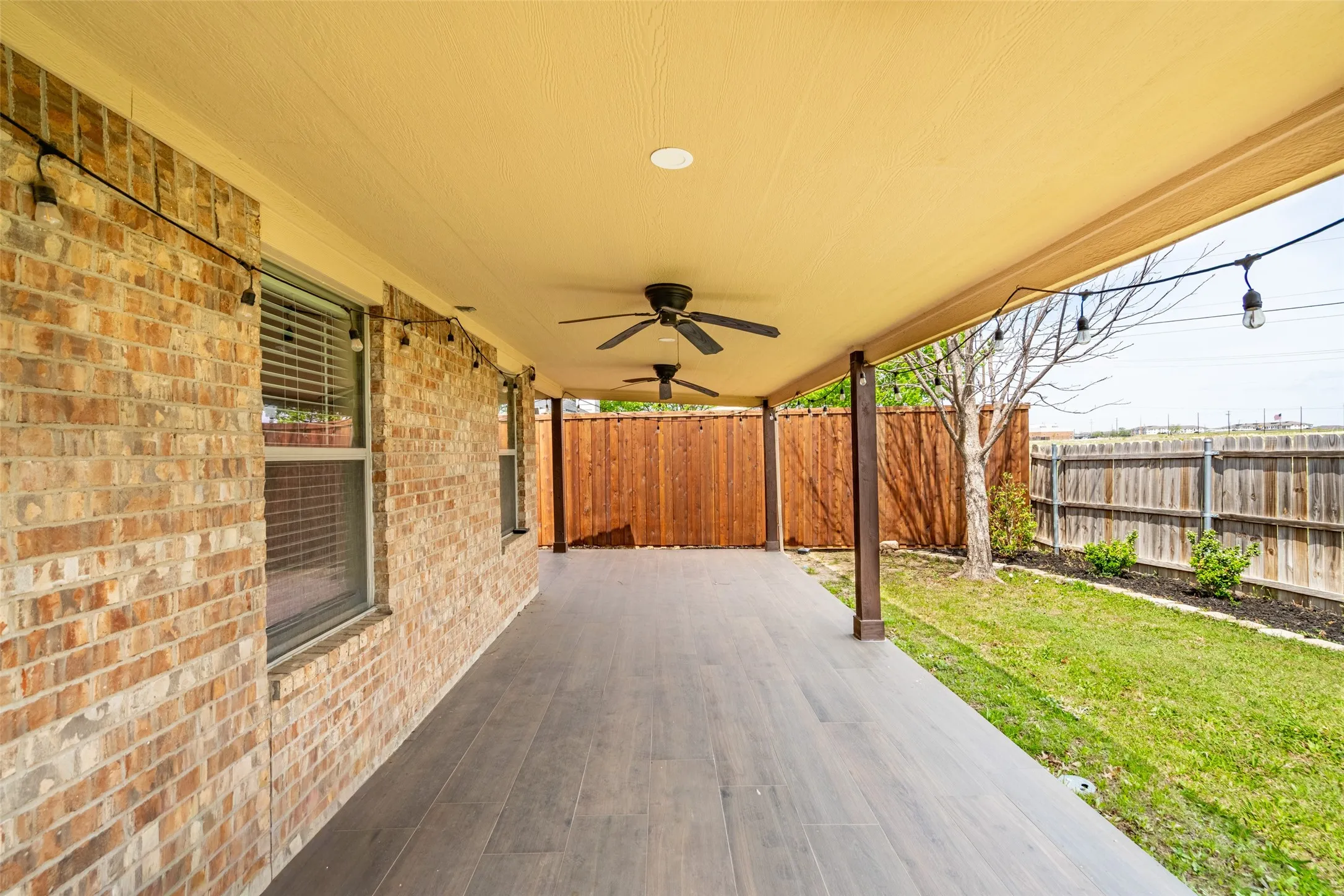 Covered patio featuring wood-finish flooring, two ceiling fans, recessed lighting, and string lights