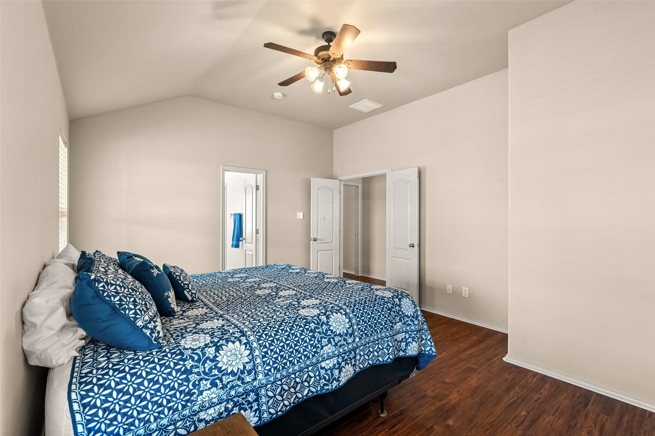 Spacious bedroom featuring vaulted ceilings, a ceiling fan, and rich wood-finish flooring