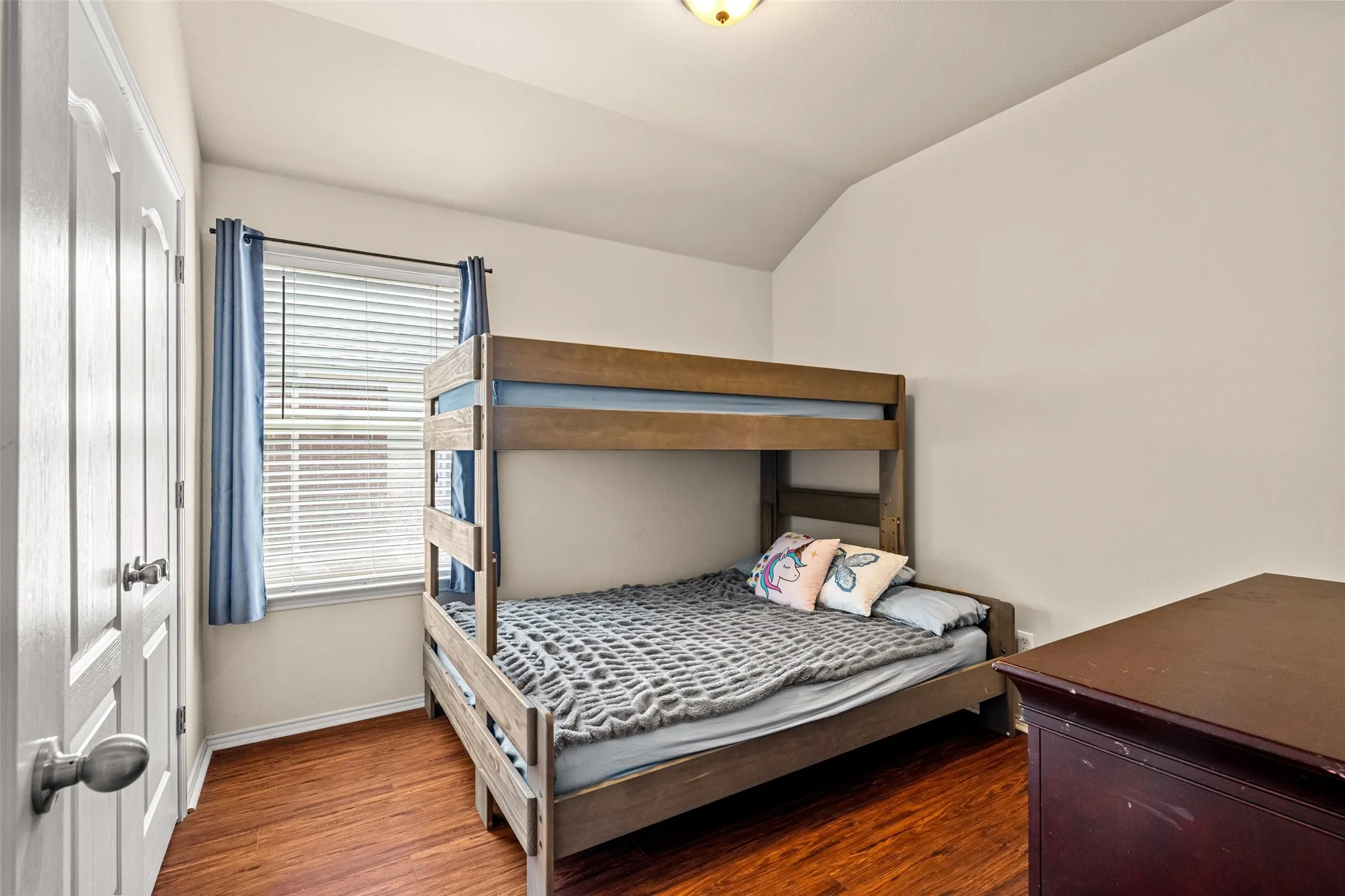 Room featuring wood-finish flooring, a window with horizontal blinds, and a paneled door