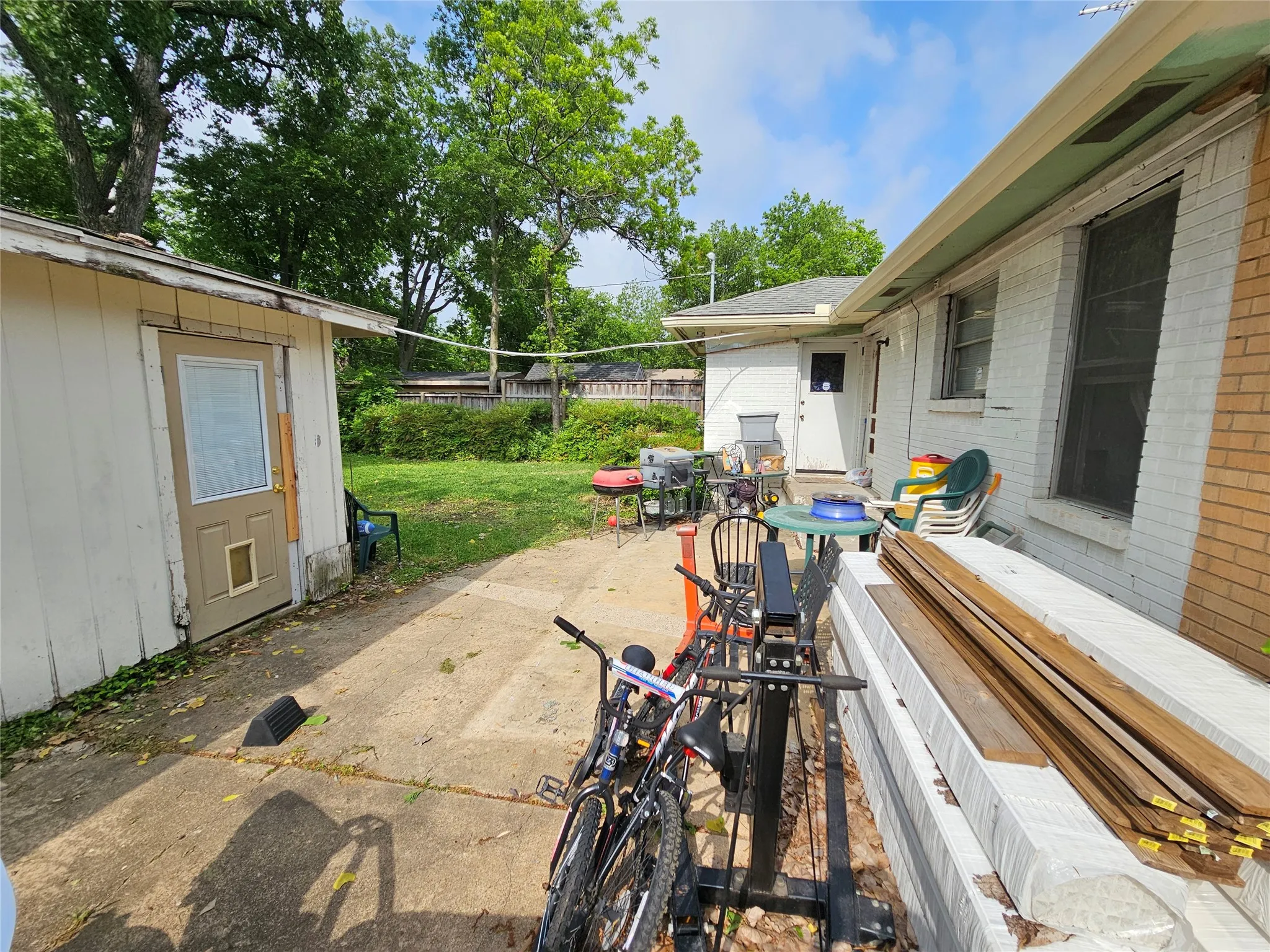 Rear patio area featuring a detached storage shed with a panel door, a concrete patio surface, and a fenced perimeter