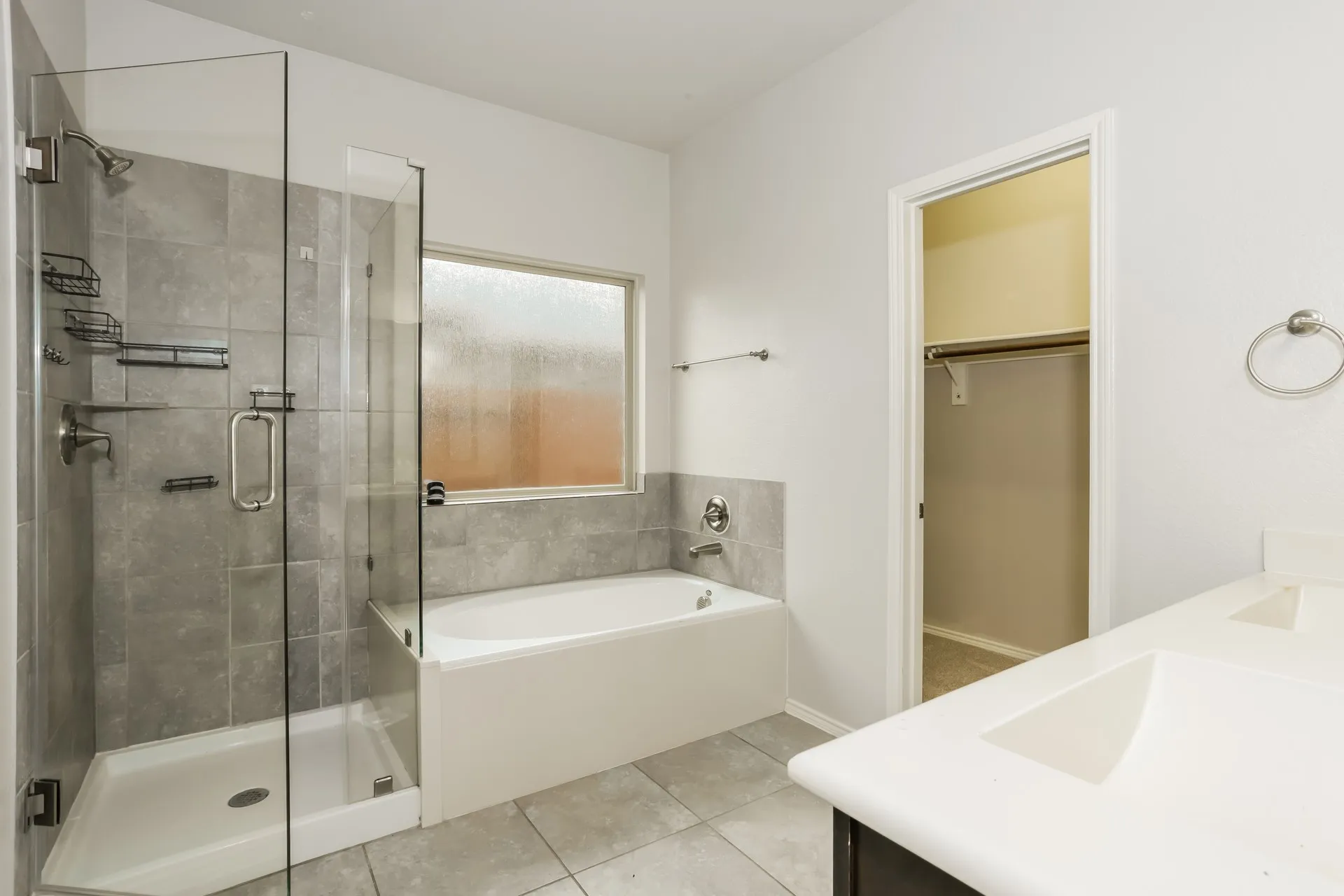 Bathroom featuring a glass-enclosed shower, a built-in bathtub with a frosted window, dual vanity sinks, and tile flooring