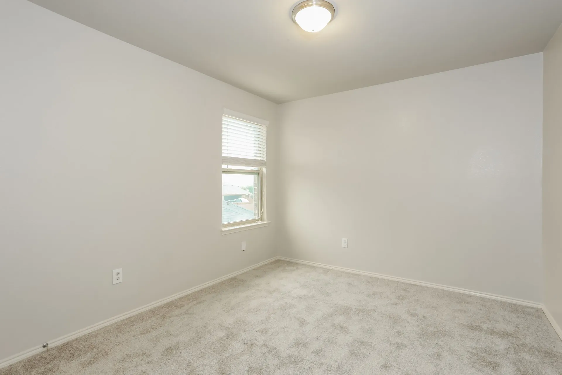 Carpeted room featuring a single window with blinds, a flush-mount ceiling light fixture, and light-toned wall paint