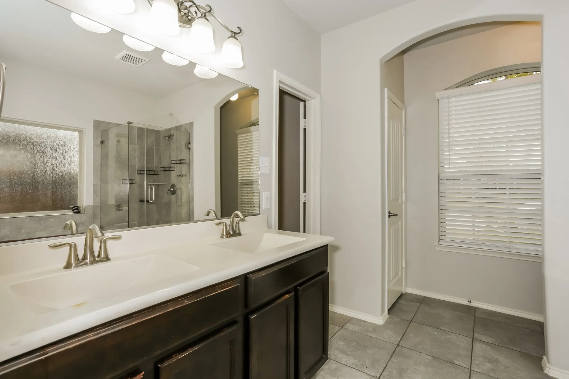 Dual vanity with integrated sinks and brushed nickel faucets, set against a wide mirror