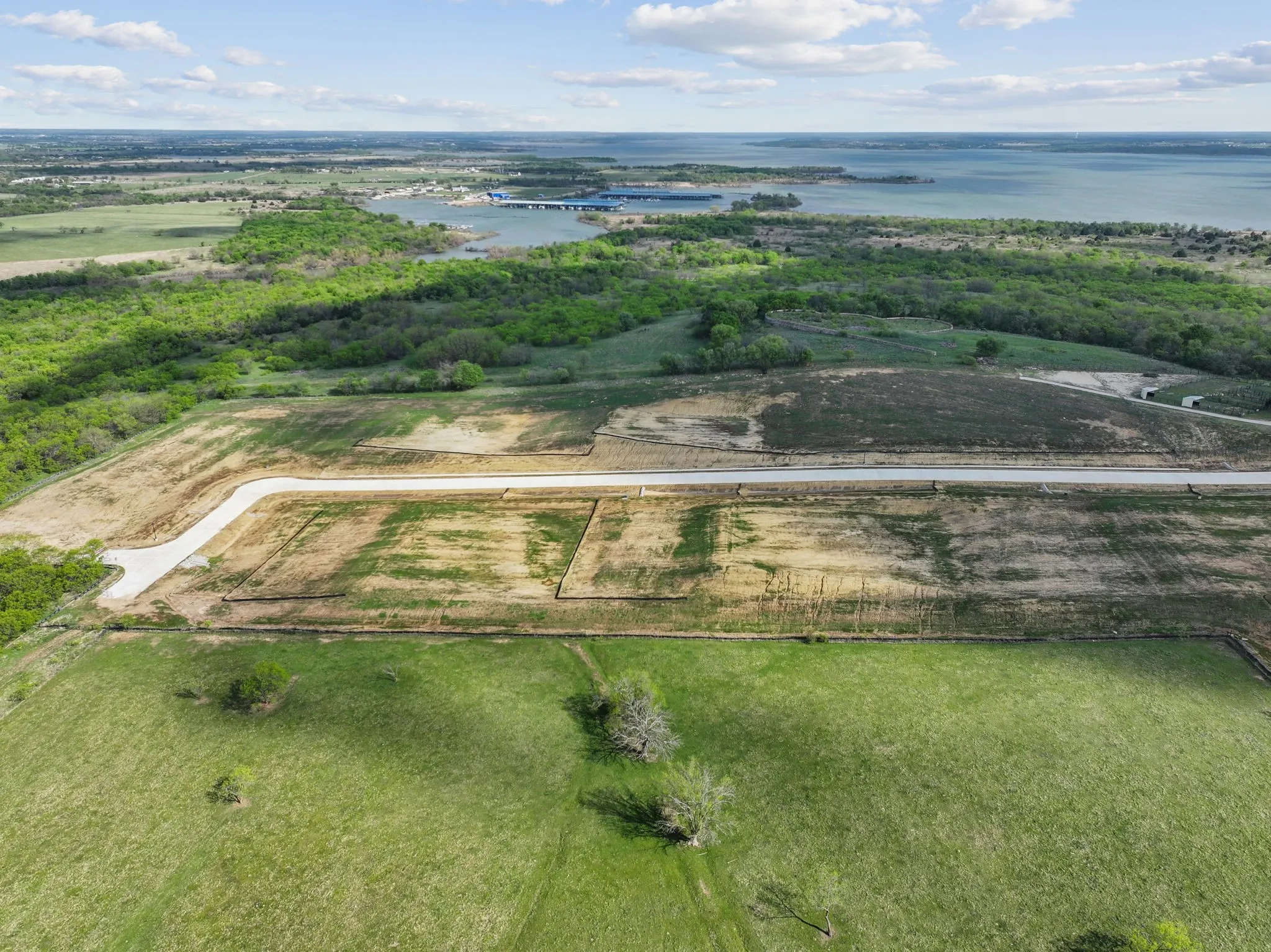 Expansive land parcel featuring multiple cleared building sites and a newly paved roadway