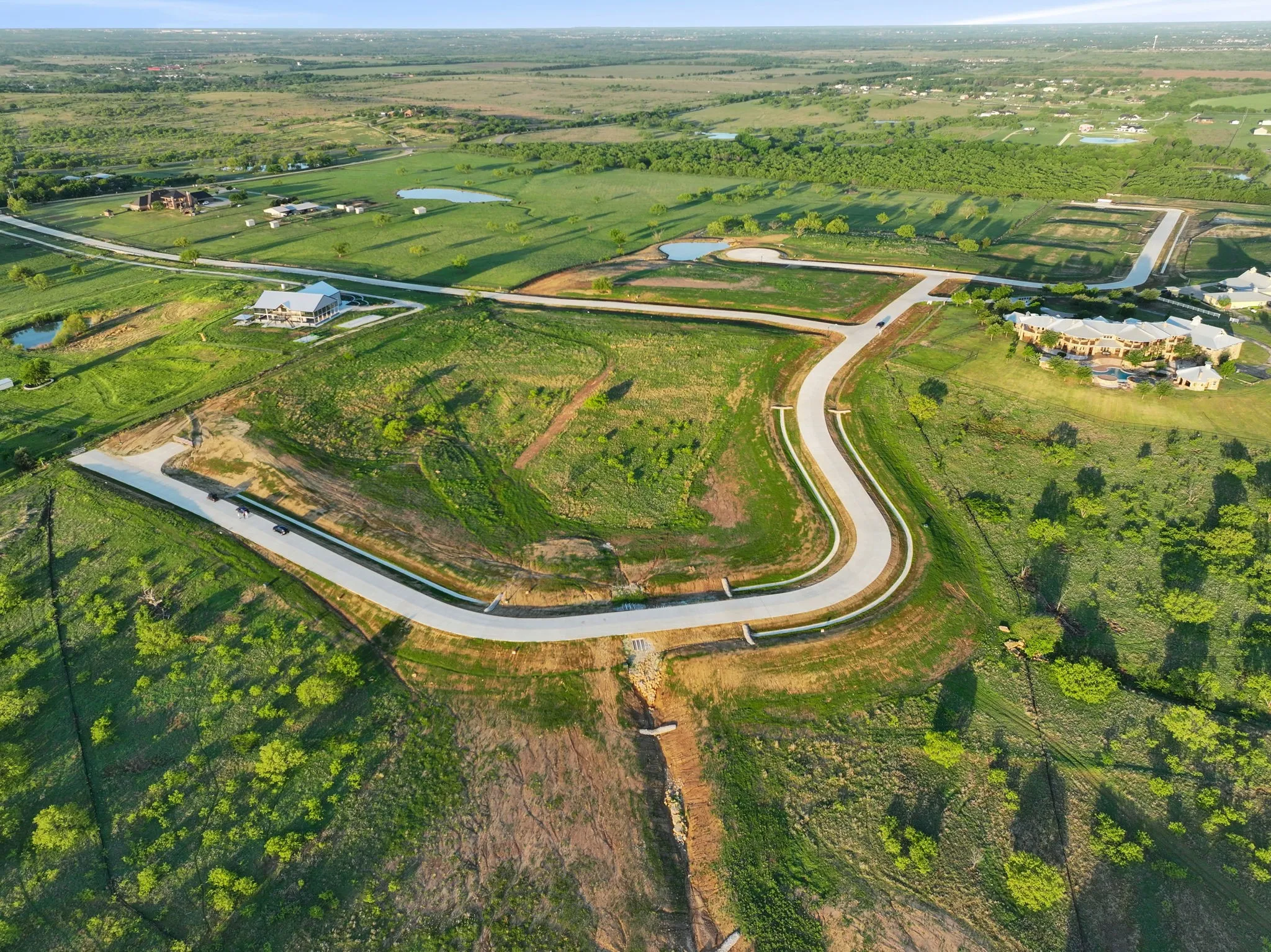 Expansive undeveloped land featuring newly paved roads, multiple buildable lots, and scattered trees