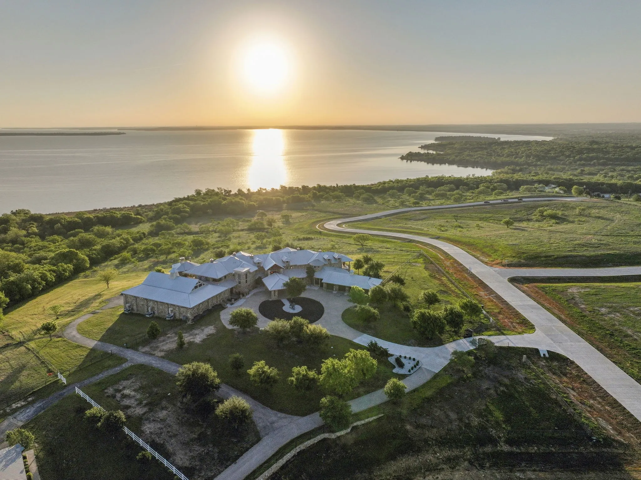 Expansive estate featuring a stone exterior, white metal roofing, and a circular driveway