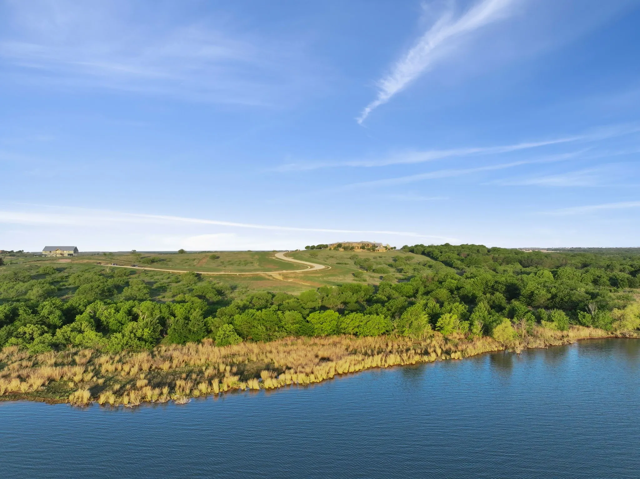 Waterfront property featuring extensive green foliage and a clear blue sky