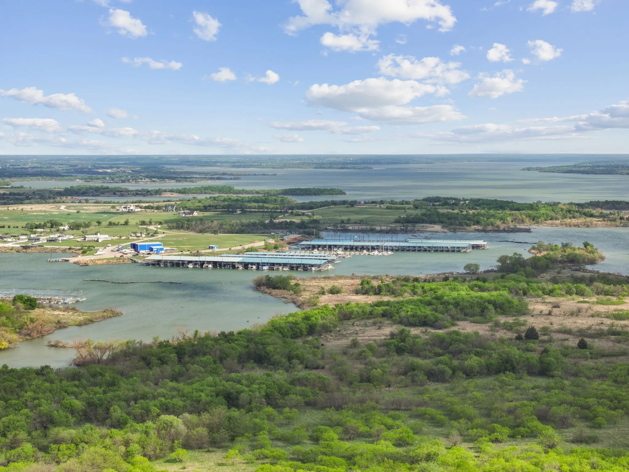 Expansive body of water surrounded by lush green foliage and distant land