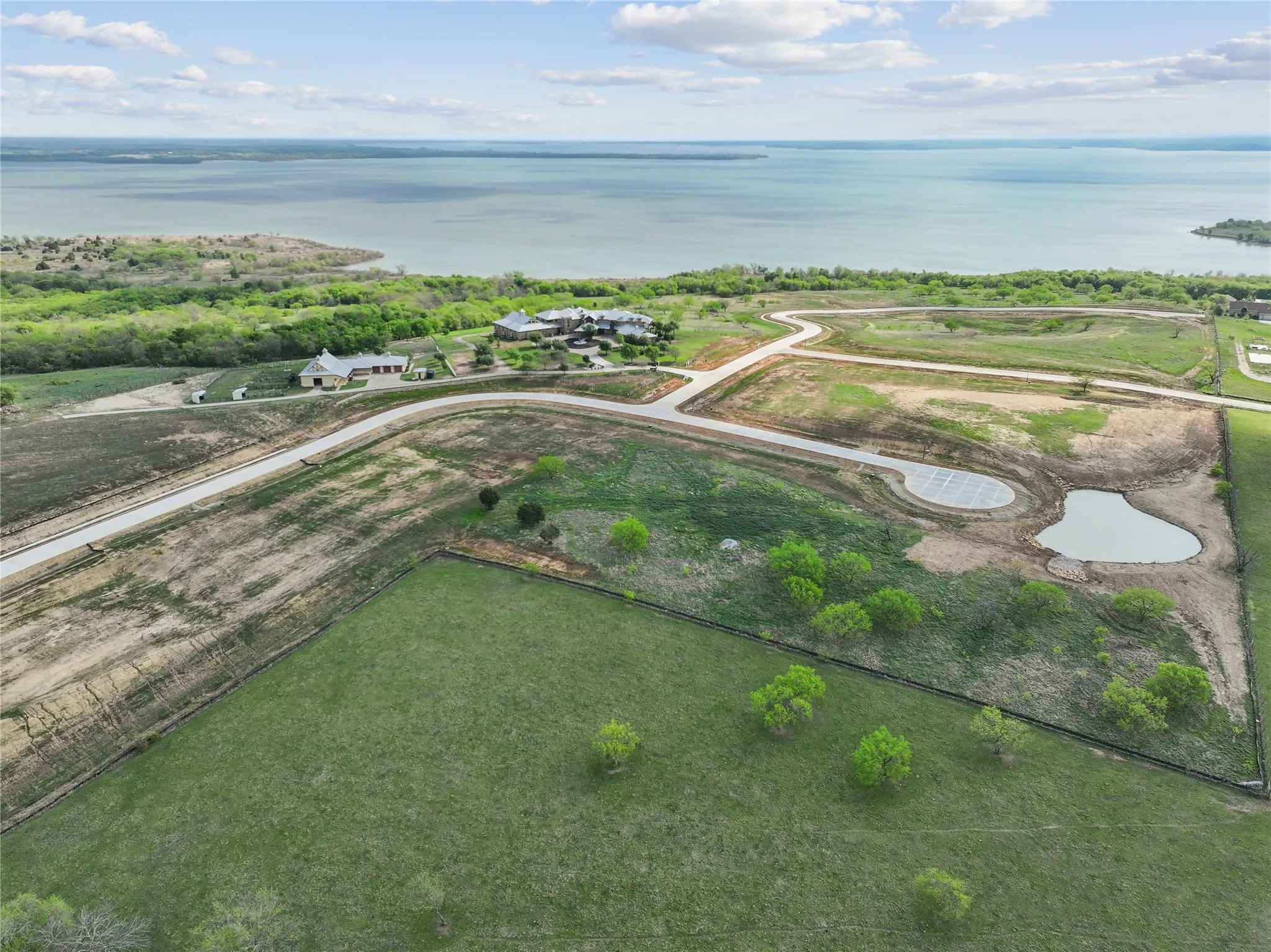 Expansive property featuring a tranquil lake, multiple residential structures, undeveloped lots, a private pond, and paved roadways