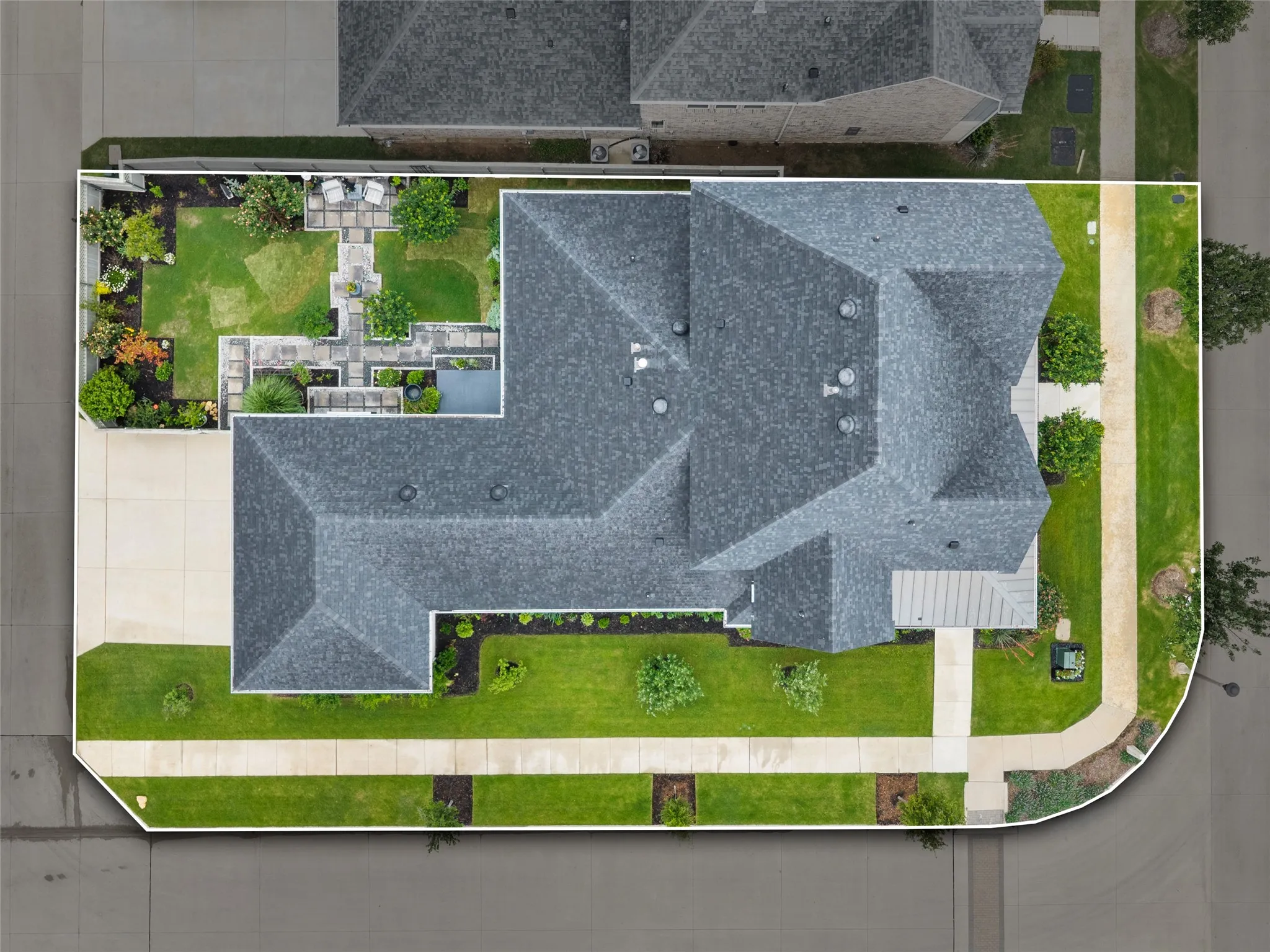 Property featuring a multi-gabled roofline, a private backyard with a structured patio, lush landscaping, and a well-maintained lawn