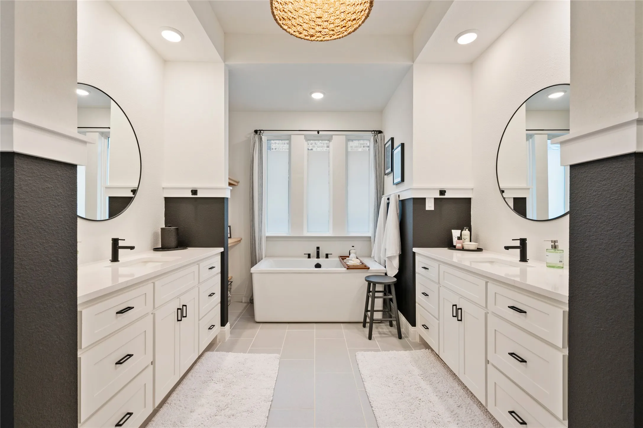 Contemporary bathroom featuring dual vanities with white cabinetry, quartz countertops, and matte black fixtures with tile flooring, plenty of natural light and a seperate shower and built in custom linen and medicine cabinet.