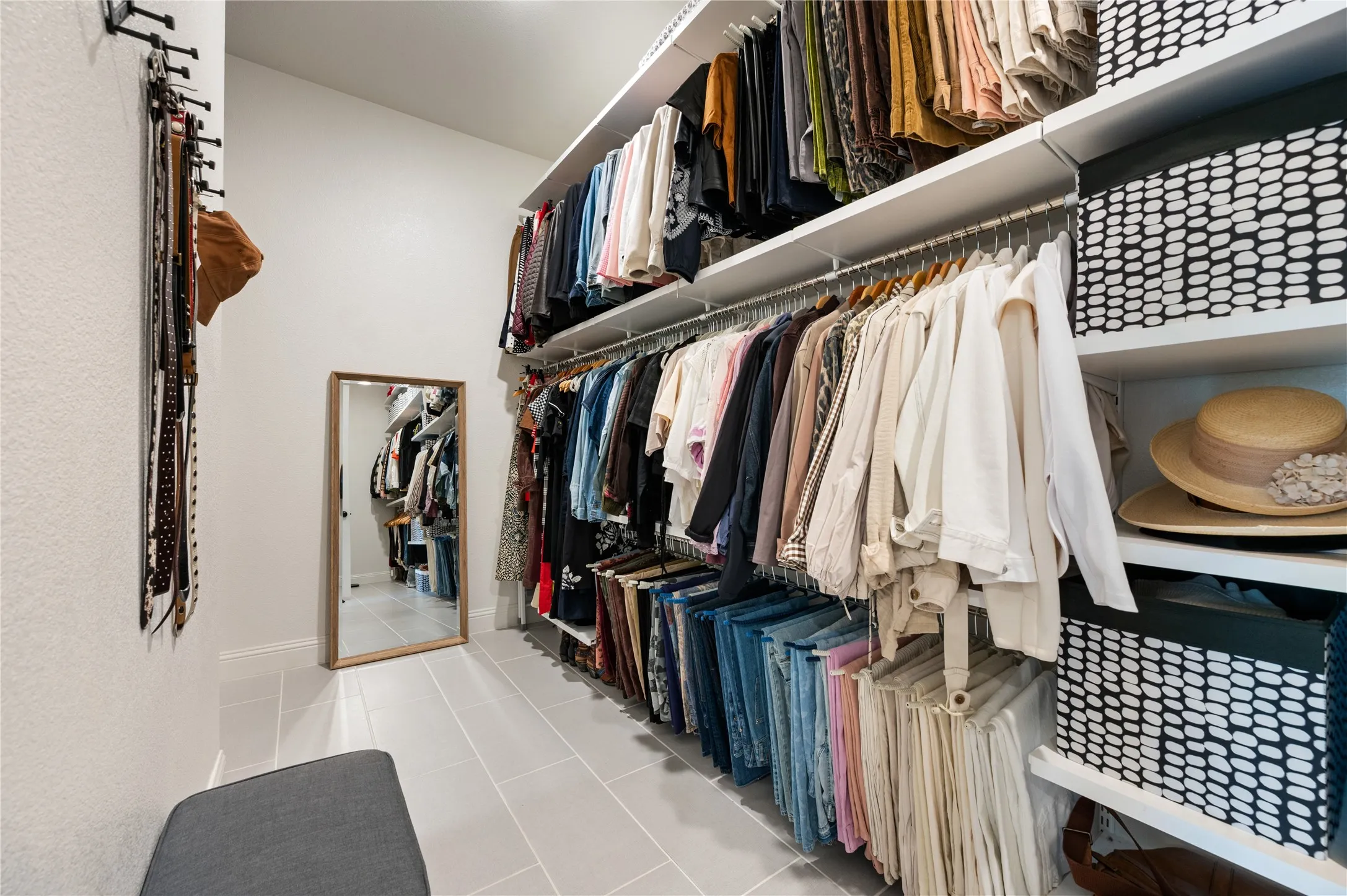 Walk-in closet featuring extensive built-in shelving, multiple hanging rods, durable flooring, and clean white walls in primary