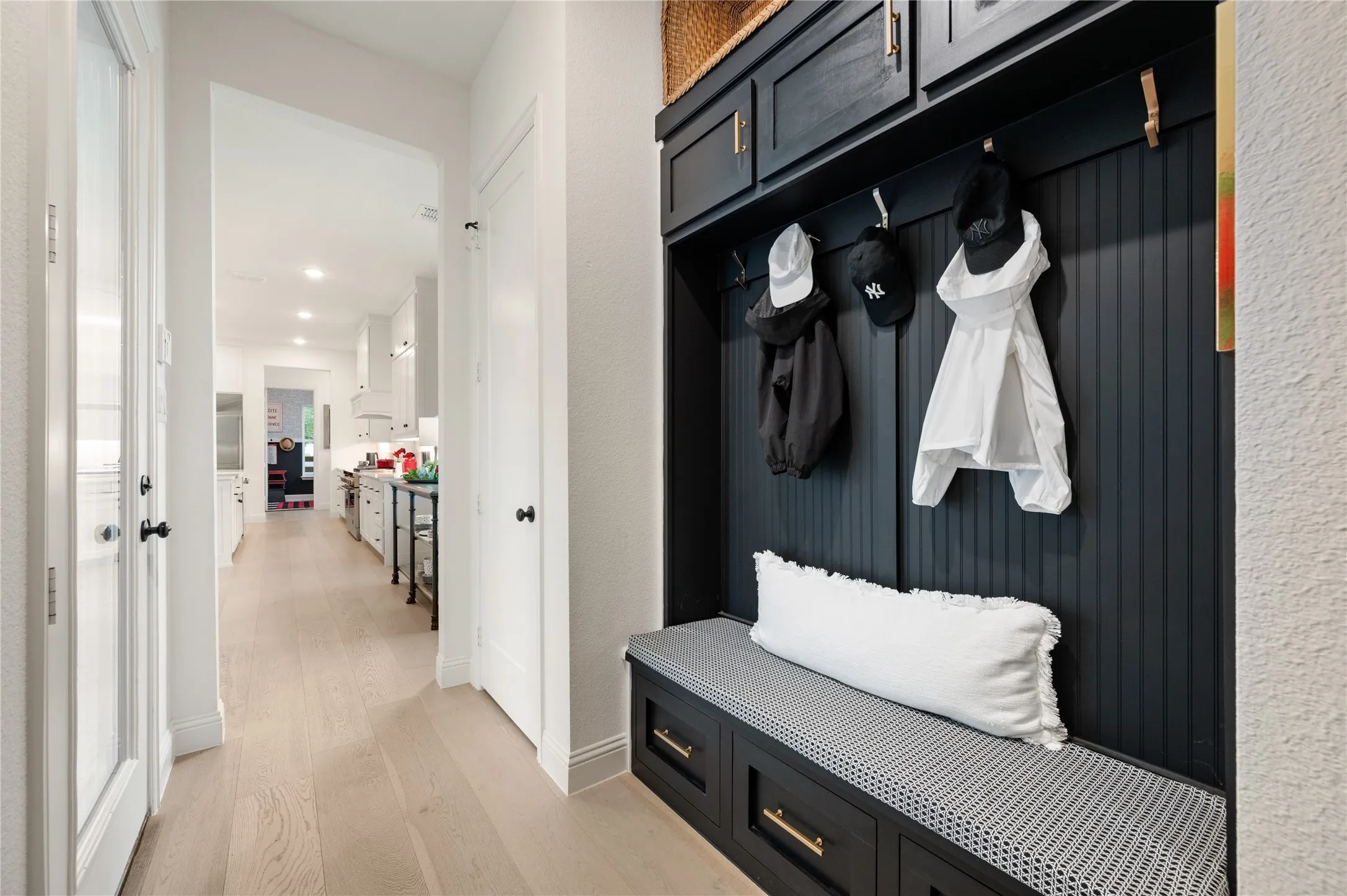 Built-in mudroom bench with beadboard backing, overhead cabinetry, and integrated storage drawers off the garage