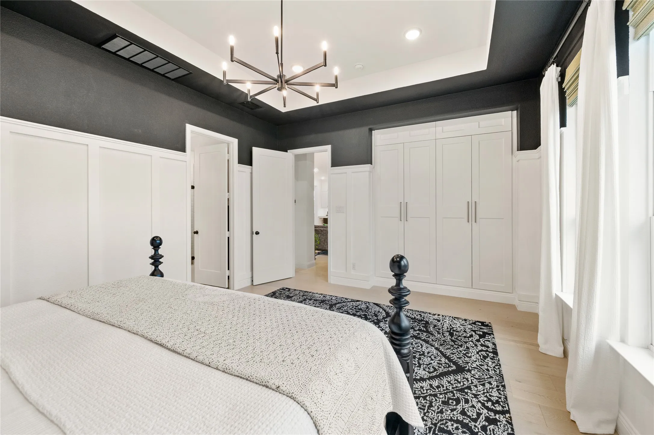 Gorgeous contemporary designed primary bedroom with wood flooring, custom wood work, built in storage, natural light and ensuite bathroom