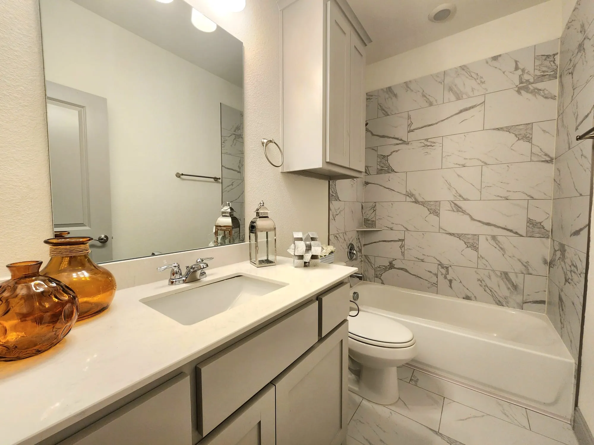 Bathroom featuring a single vanity with an integrated sink, polished chrome faucet, and light-toned solid surface countertop