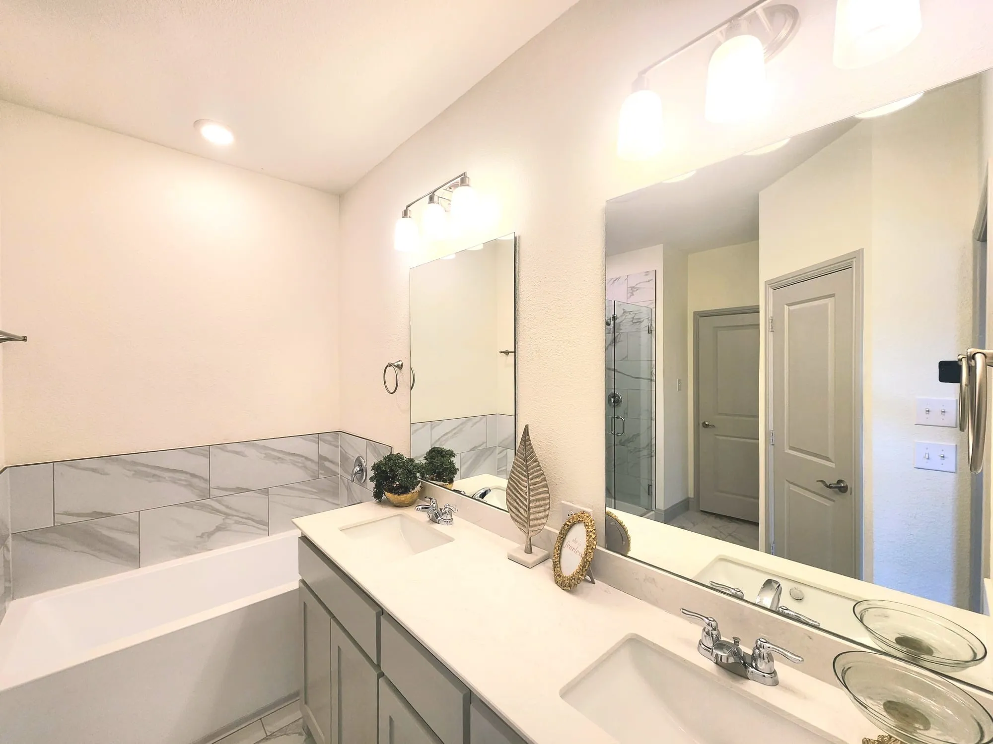 Dual sink vanity with white countertop, chrome fixtures, and integrated mirrors
