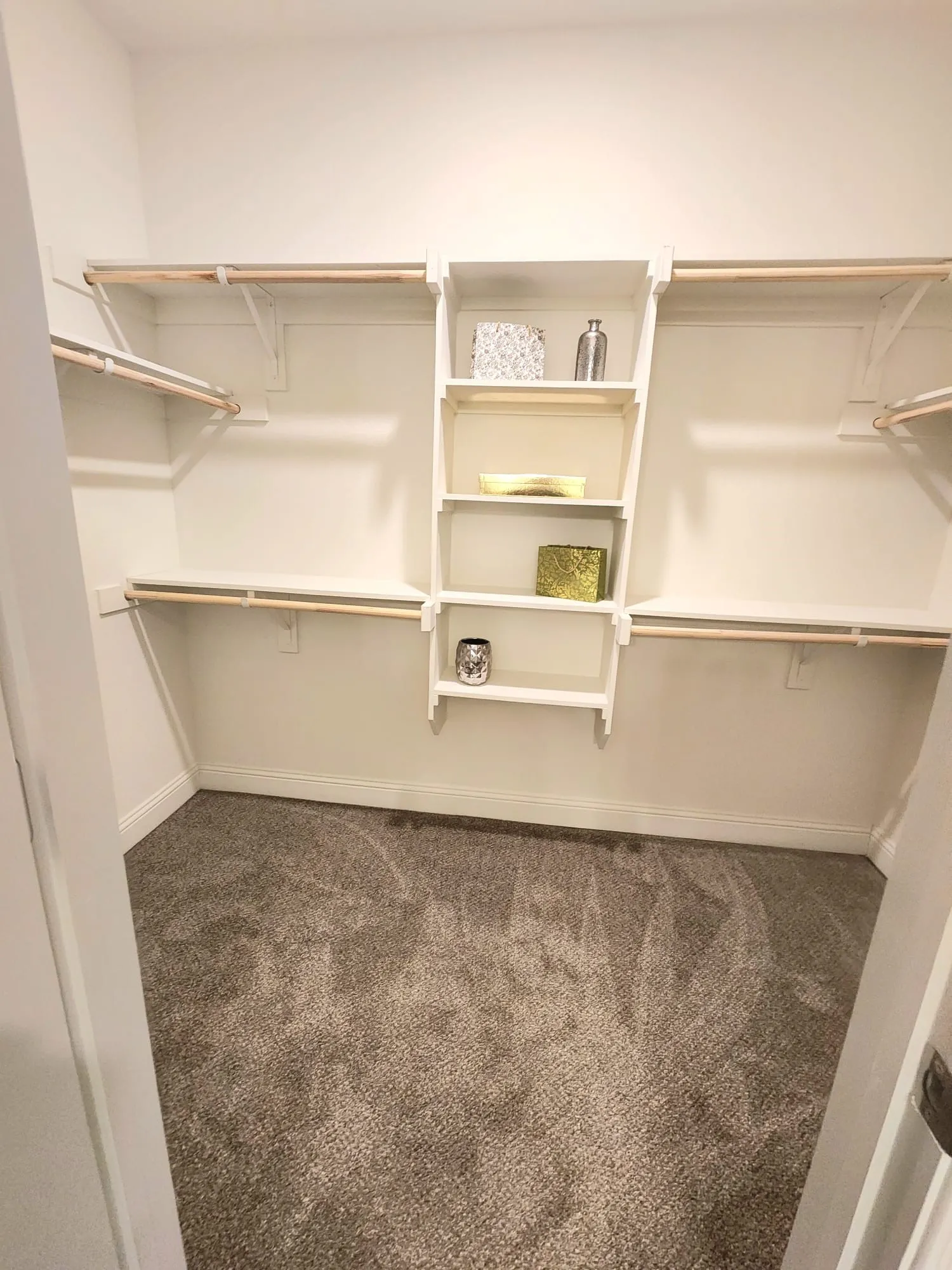 Spacious closet featuring built-in shelving, multiple hanging rods, and soft carpet flooring