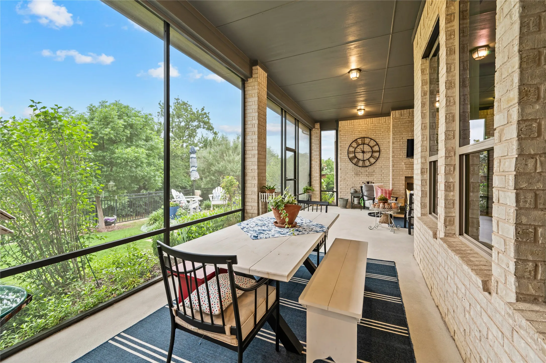 Expansive covered patio featuring a light brick exterior, concrete flooring, a dark ceiling with recessed lighting, and a ceiling fan