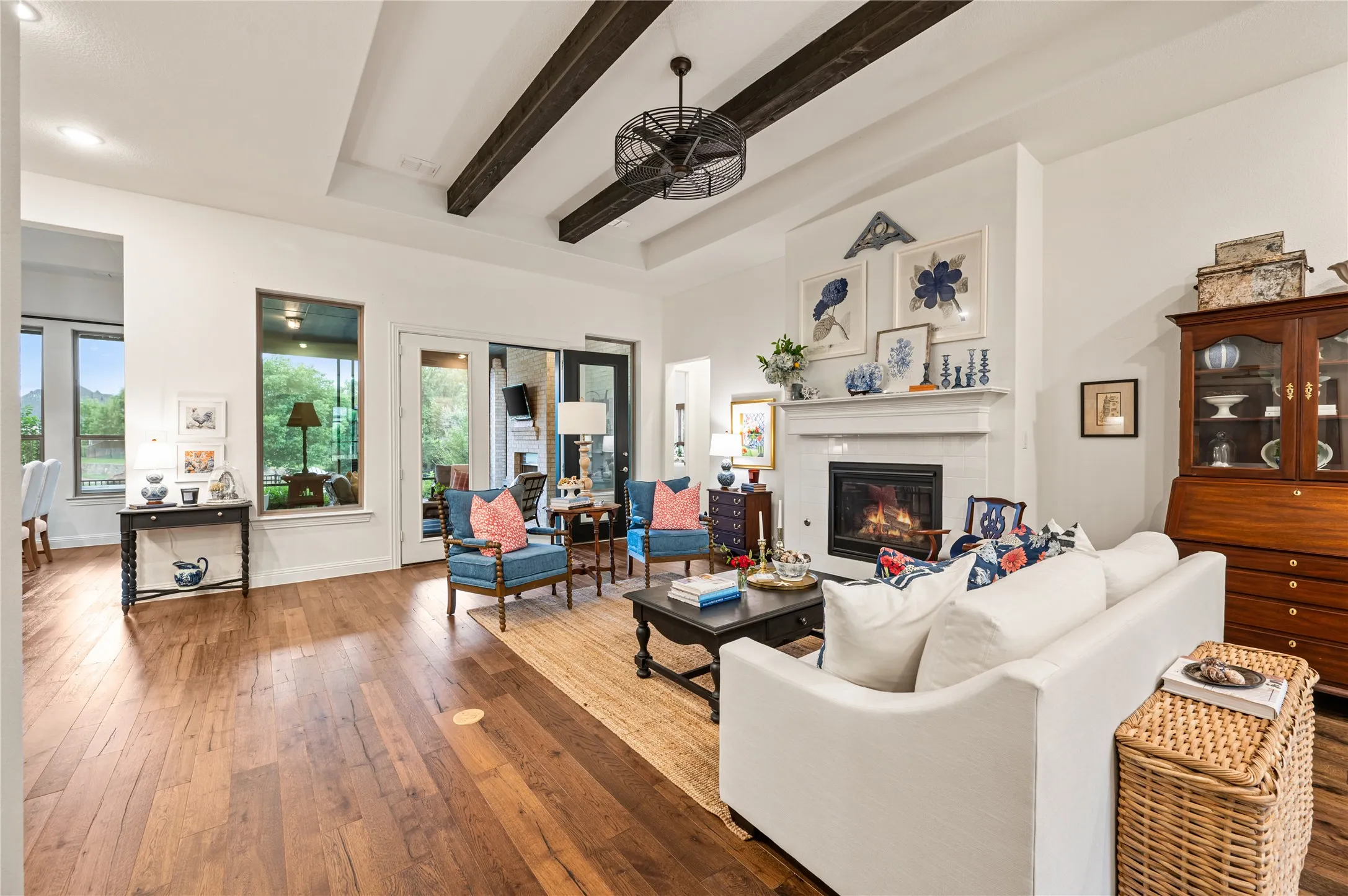 Open-concept living space featuring wood flooring, exposed ceiling beams, recessed lighting, and a modern ceiling fan with views of kitchen and dining space