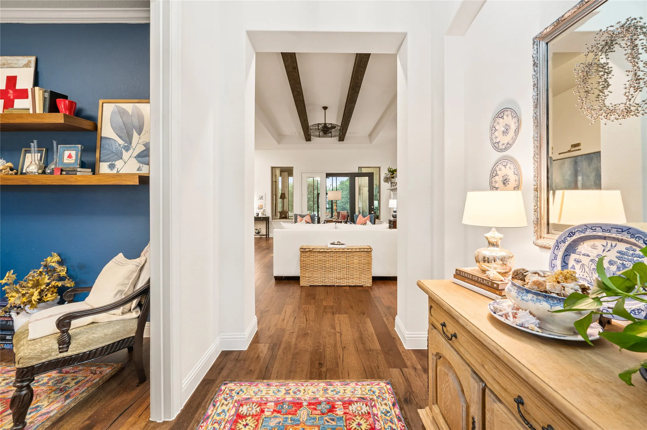 Archway entry to a living space featuring wood-finish flooring, white baseboards, and a coffered ceiling with exposed wood beams